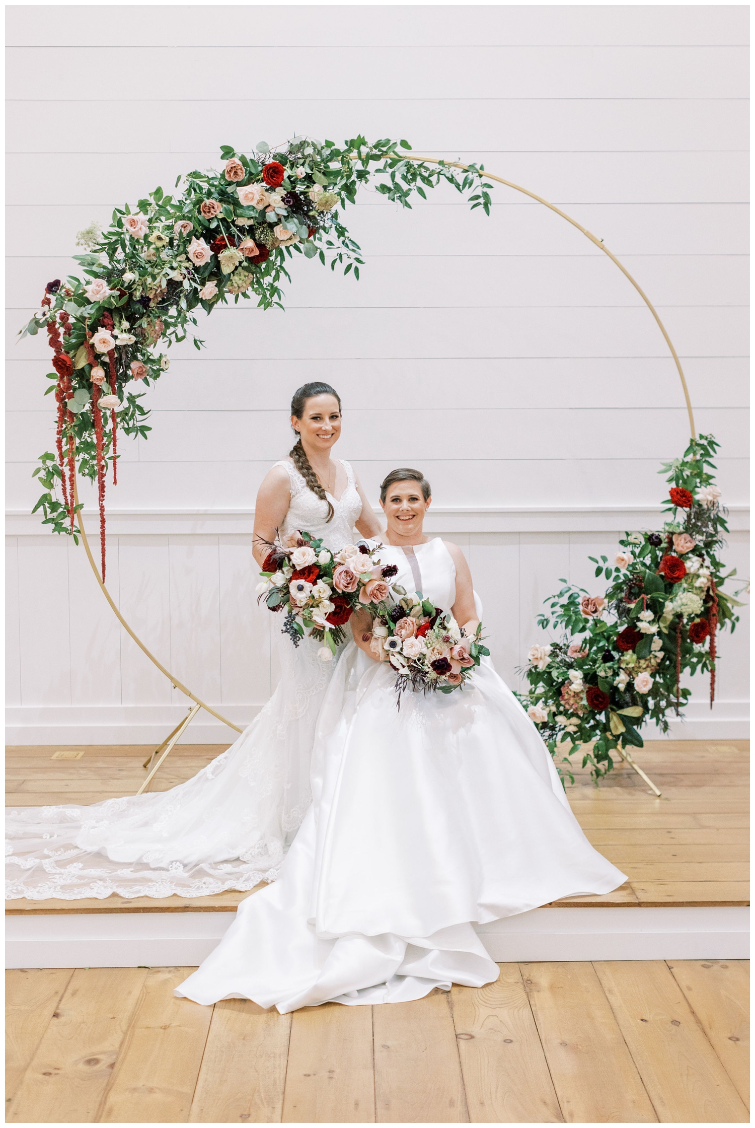 circular floral hoop ceremony set up with two brides posing