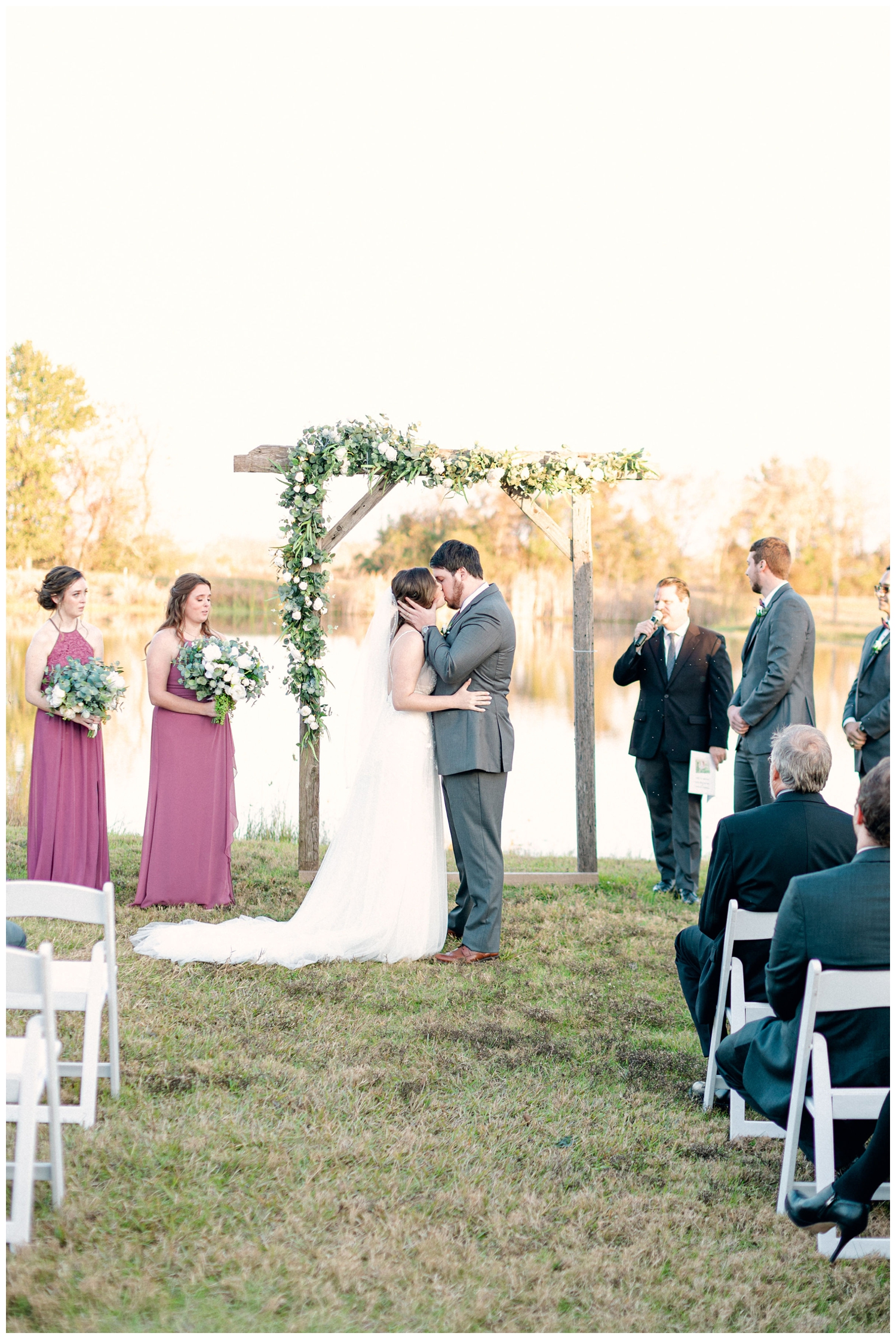 first kiss husband wife under floral arch at Beckendorff Farms Wedding
