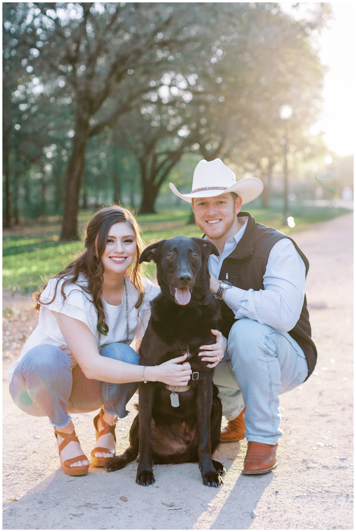 engaged couple squatting and posing with black dog