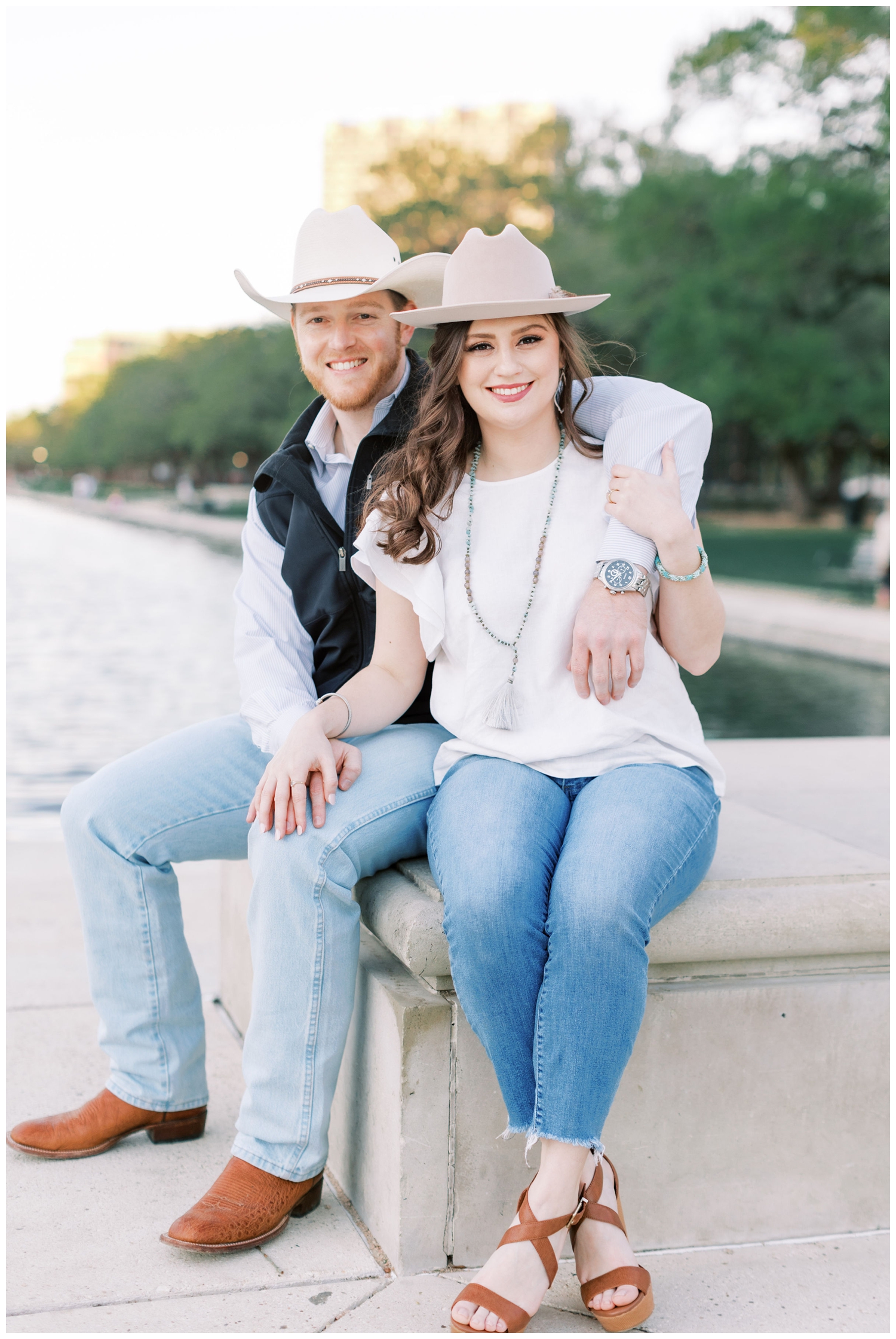 engaged couple smiling in denim jeans and cowboy hats