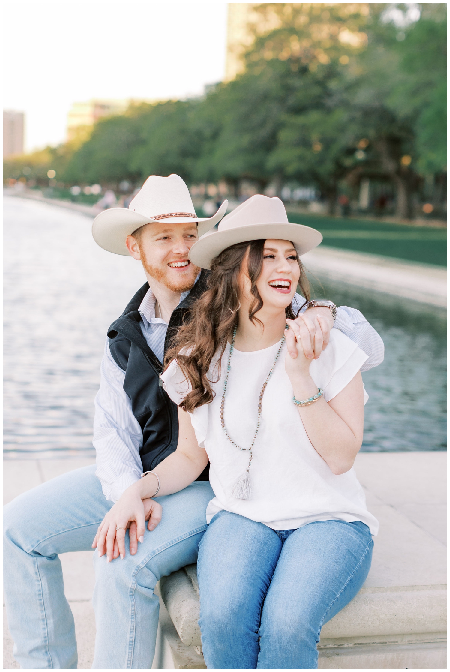 bride and groom in jeans and hats sitting by fountain at Hermann Park