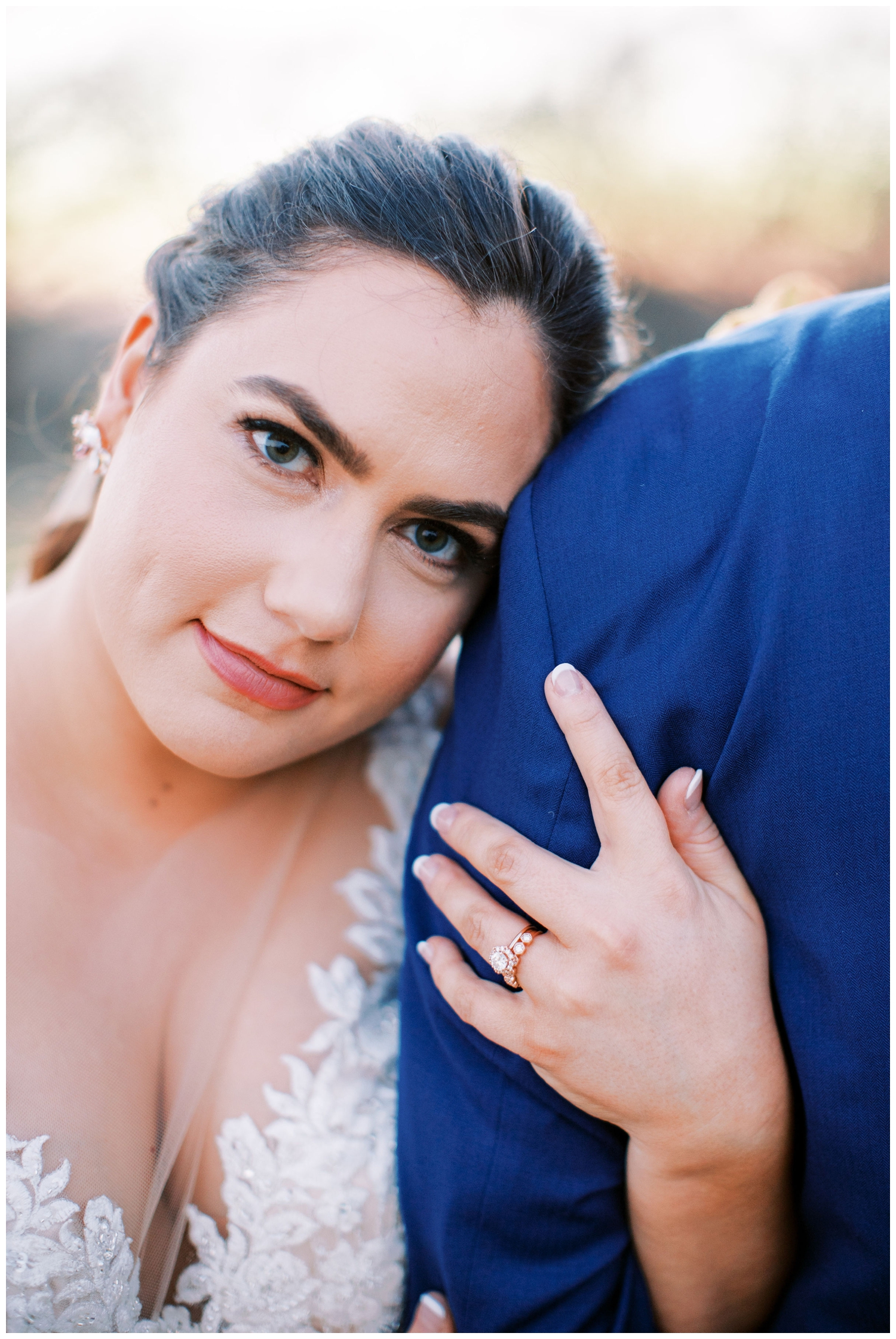 bride looking at camera holding grooms shoulder