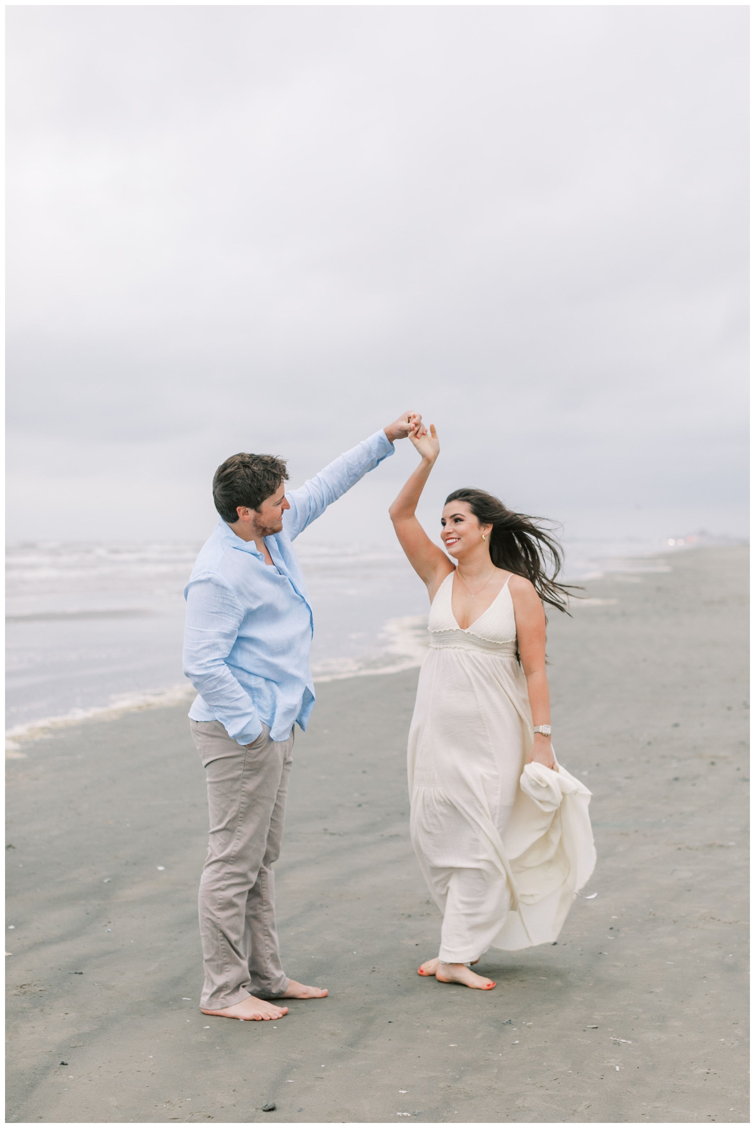 groom twirling his bride for Galveston engagement session at Galveston Beach
