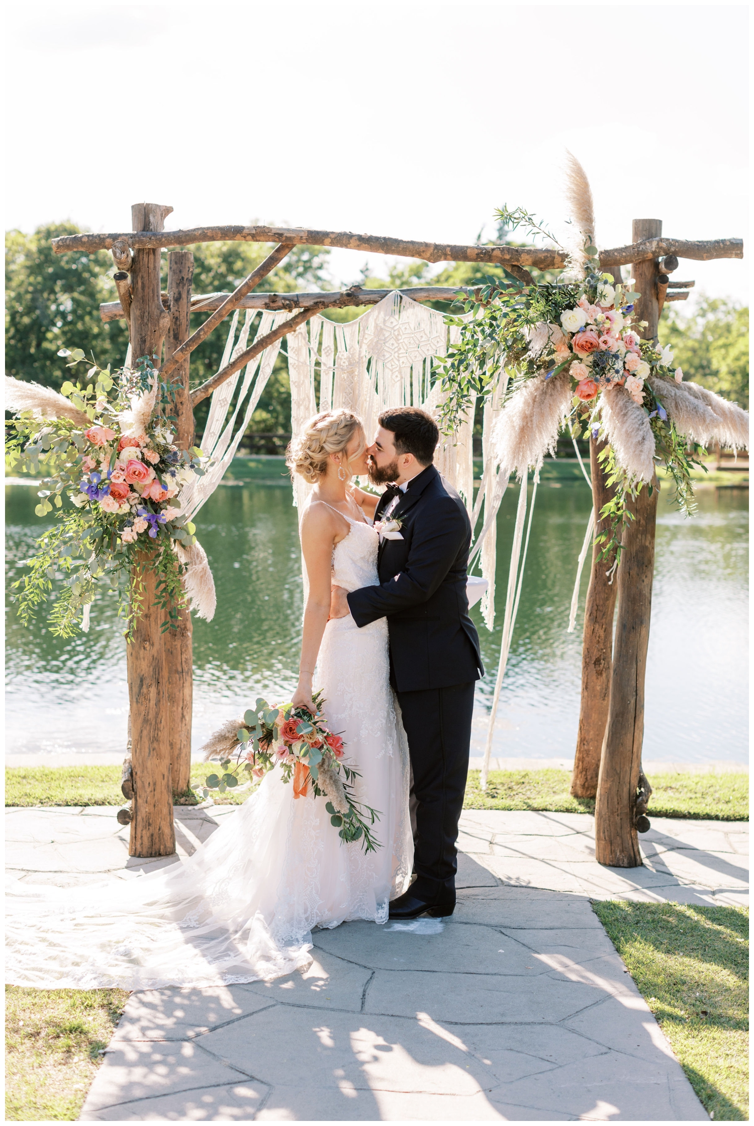 ceremony arch Peach Creek Ranch Wedding venue with bride and groom standing and kissing in front of the water