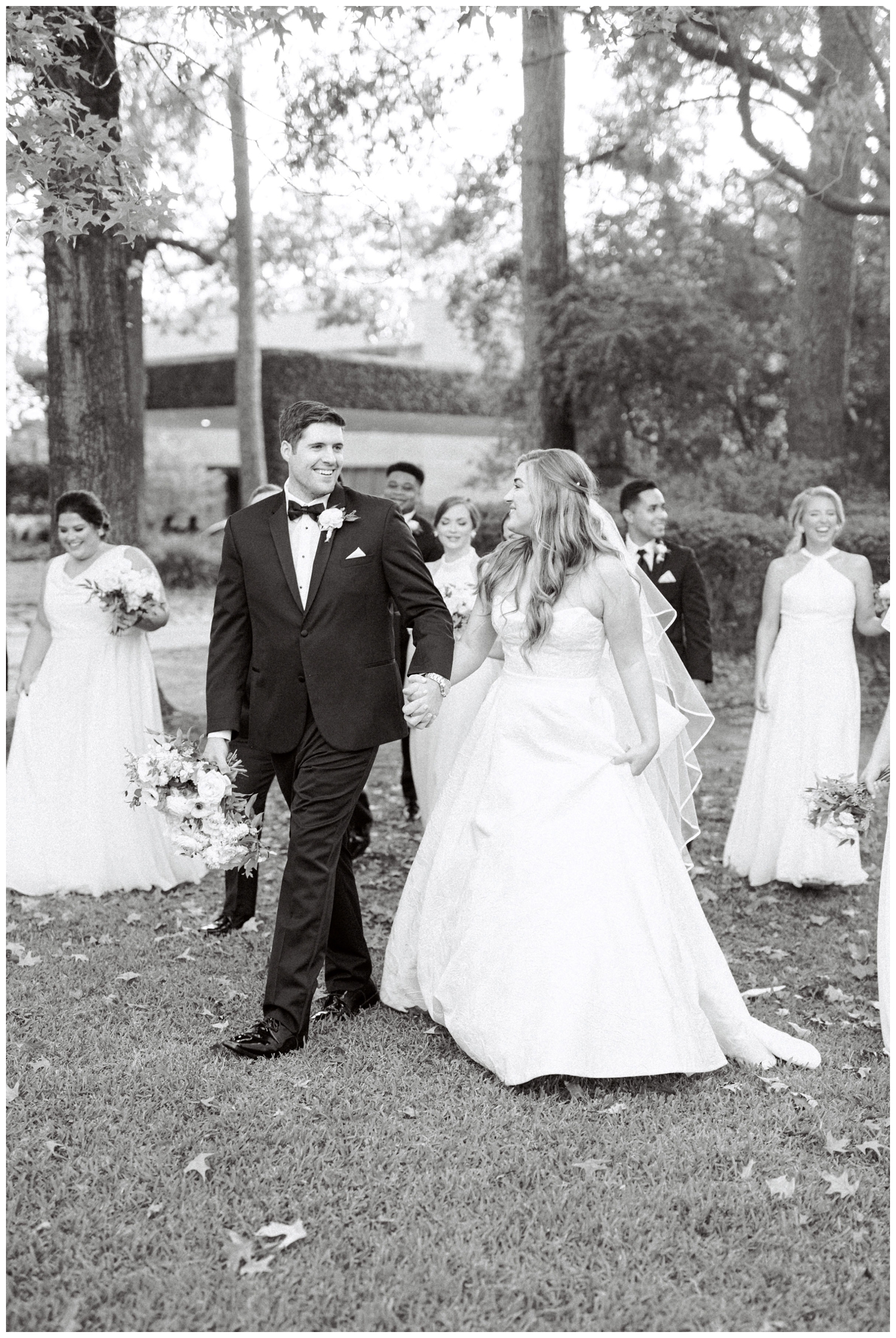 black and white portrait with bride and groom holding hands and walking