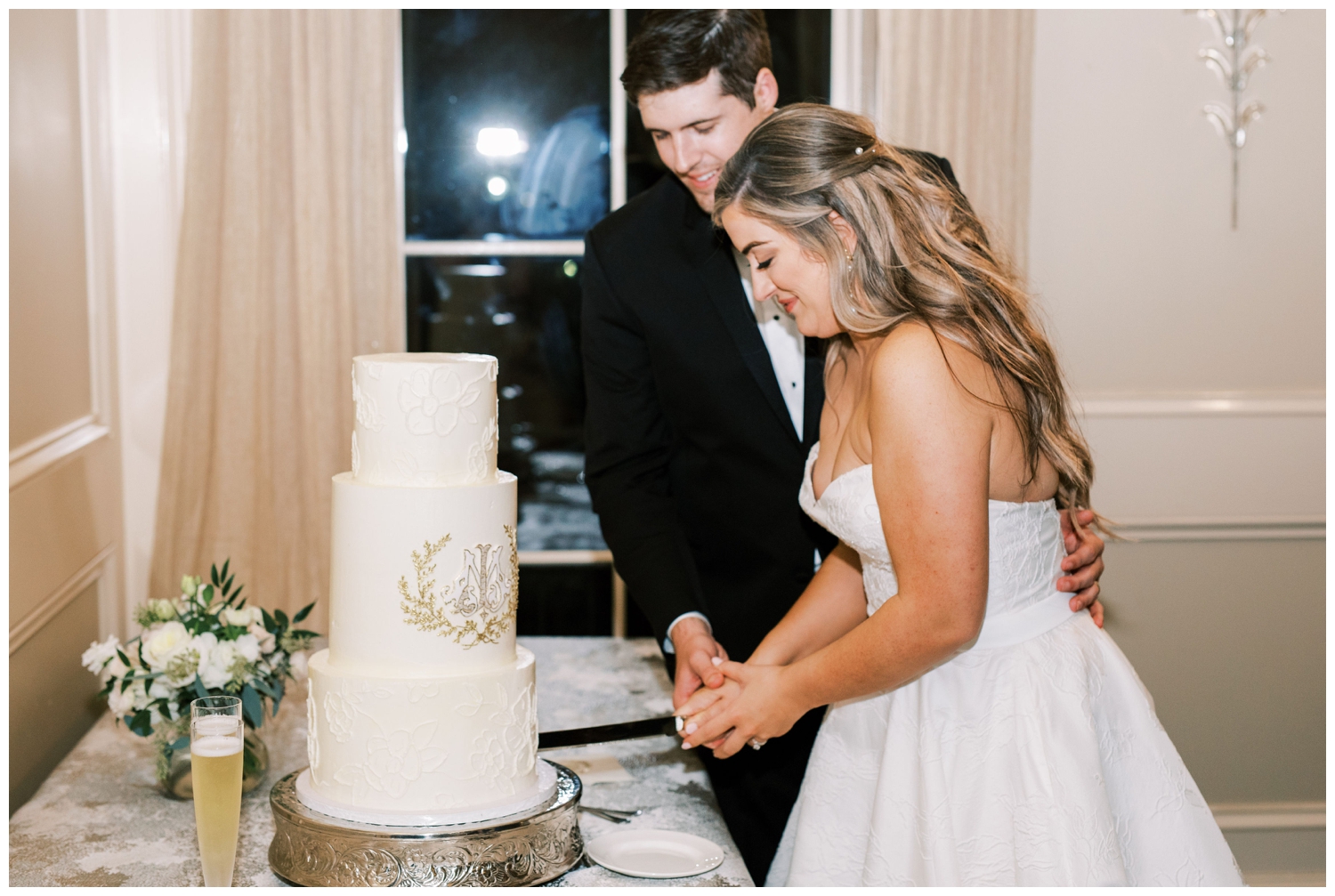 newlyweds cutting all white cake with gold monogram after The Houstonian Hotel wedding