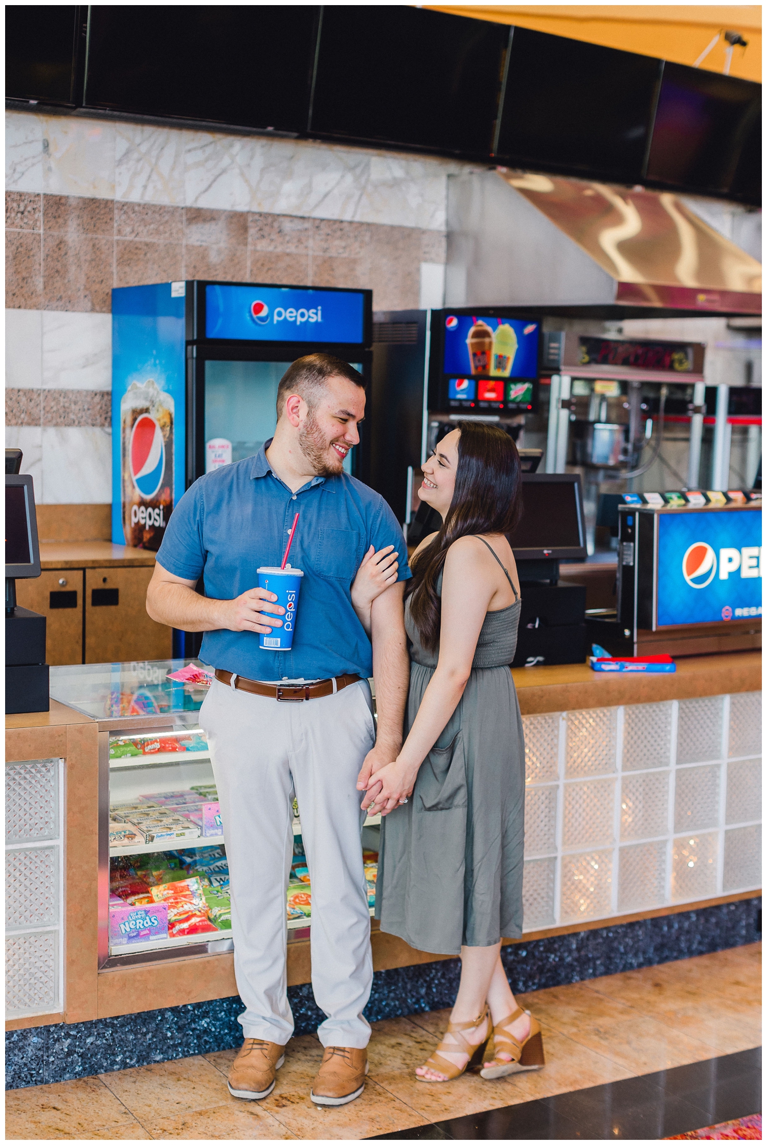 couple holding hands by soda fountain during movie theater engagement session