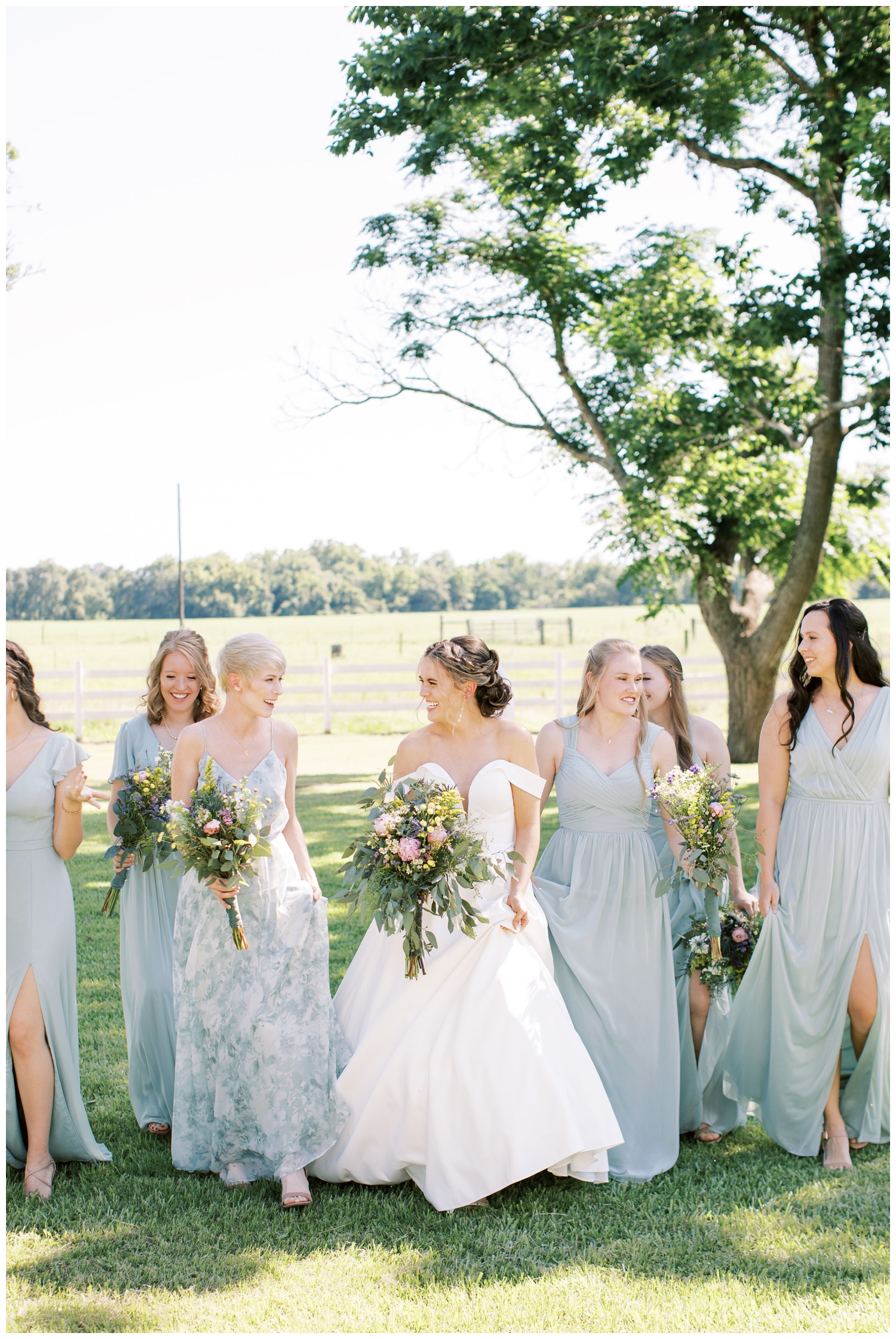 bride walking on the grass with bridesmaid at Houston white barn wedding