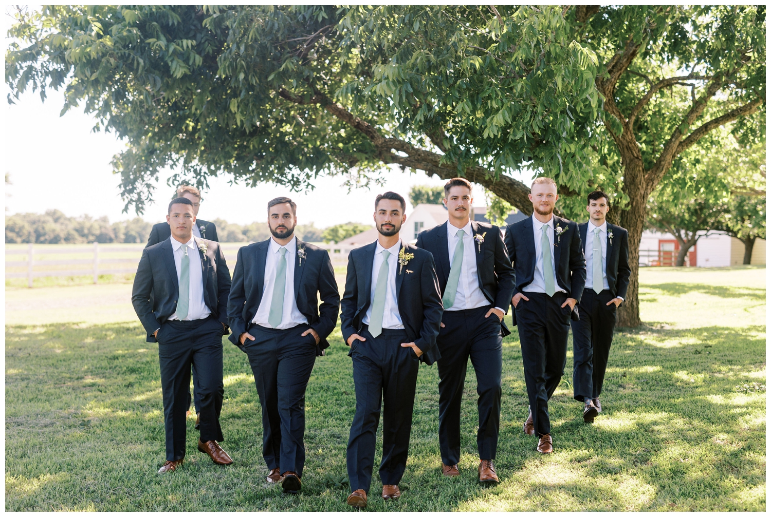 groom walking under a tree with groomsmen at The Grand Texasa