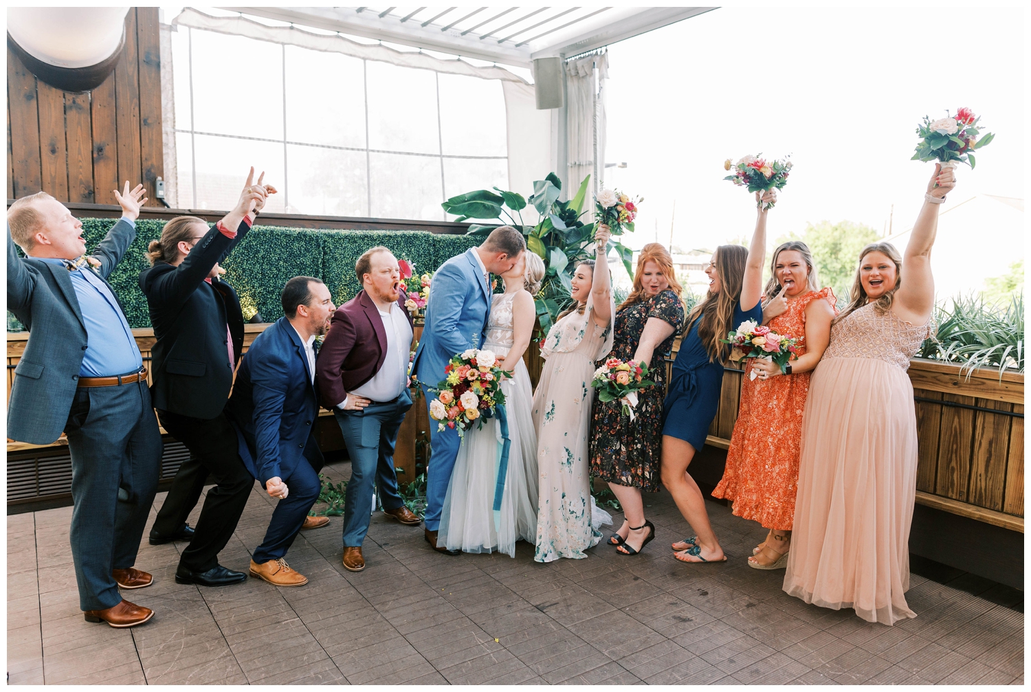 bride and groom kissing with bridal party around them