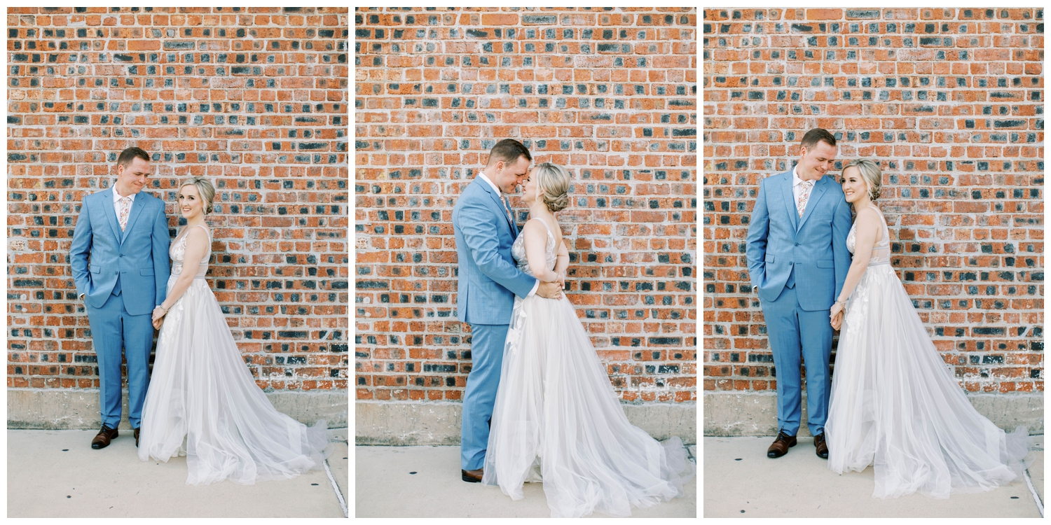 brick wall background with bride and groom posing