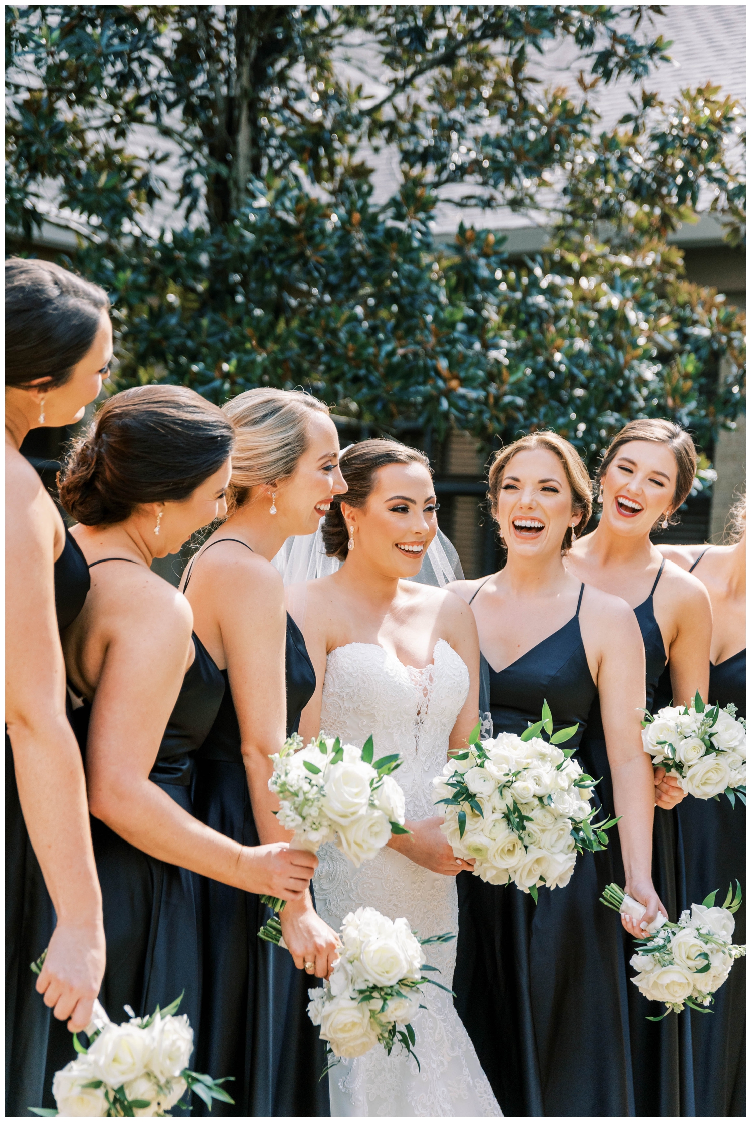 bride with bridesmaids in black dresses white bouquets laughing Houston Junior League wedding