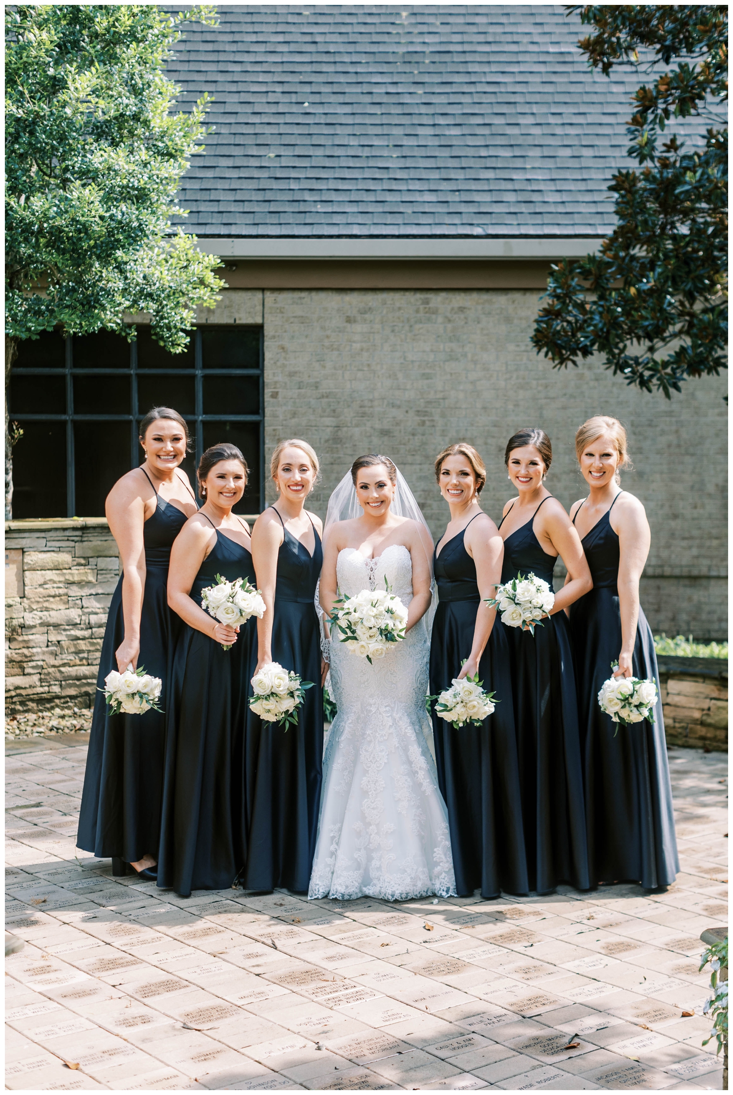 bride and bridesmaids in black dresses holding all white bouquets