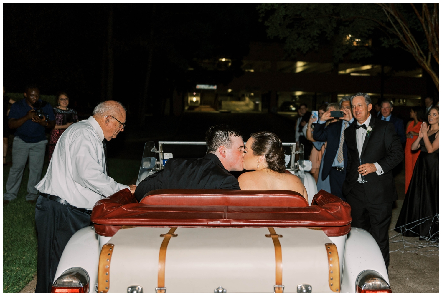 bride and groom sitting in vintage car and kissing at end of Houston Junior League wedding reception