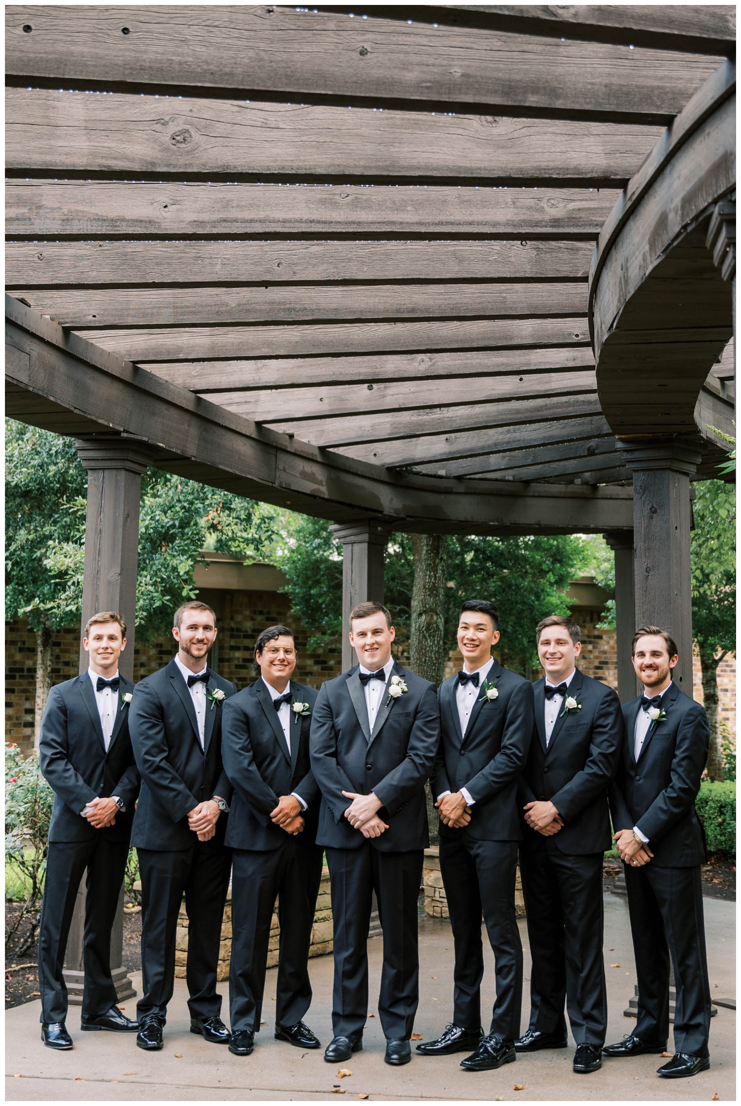 groom and groomsmen standing in a line black tuxes Houston Junior League wedding