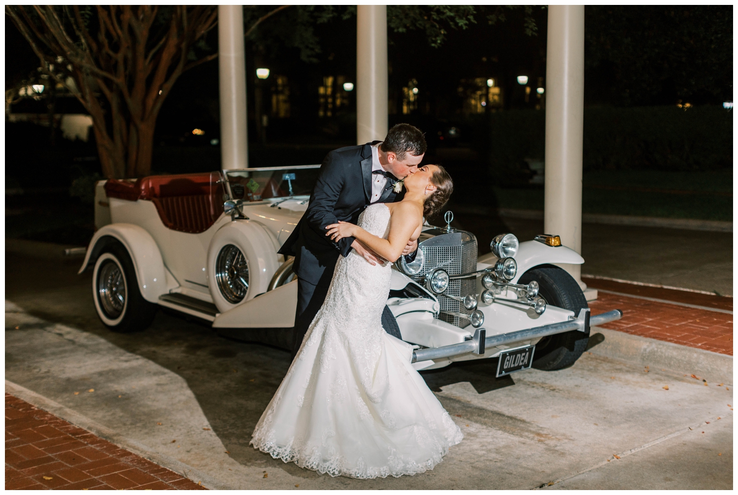 bride and groom kissing in front of vintage car outside Junior League wedding reception