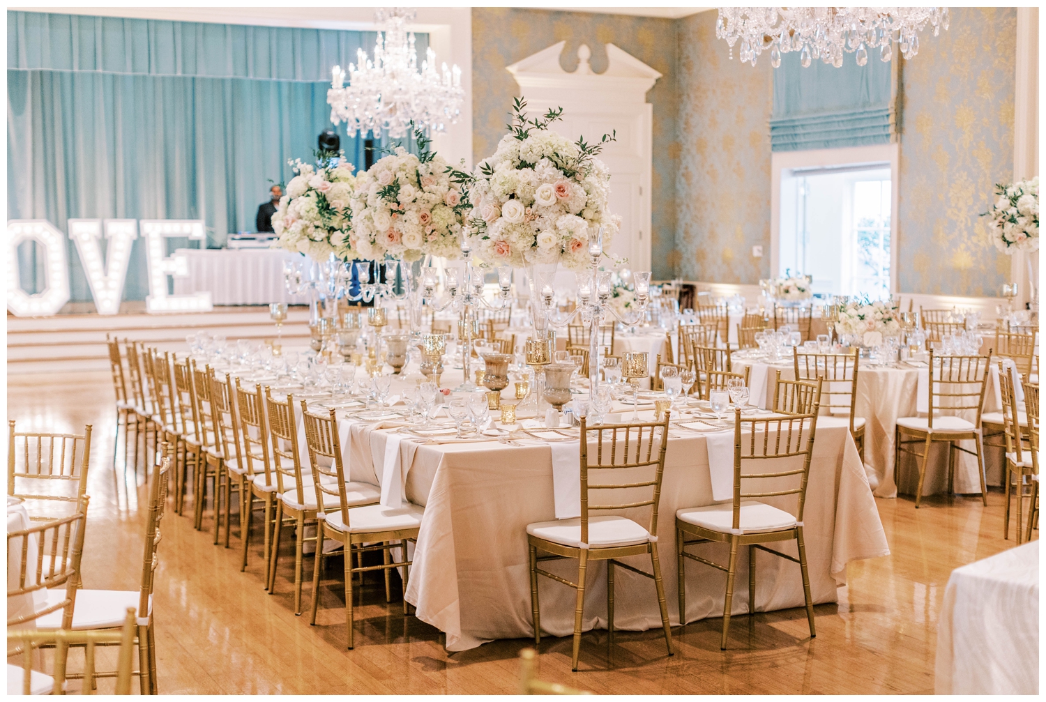 white and gold reception tables with florals at bride and groom kissing in front of vintage car outside Junior League wedding reception
