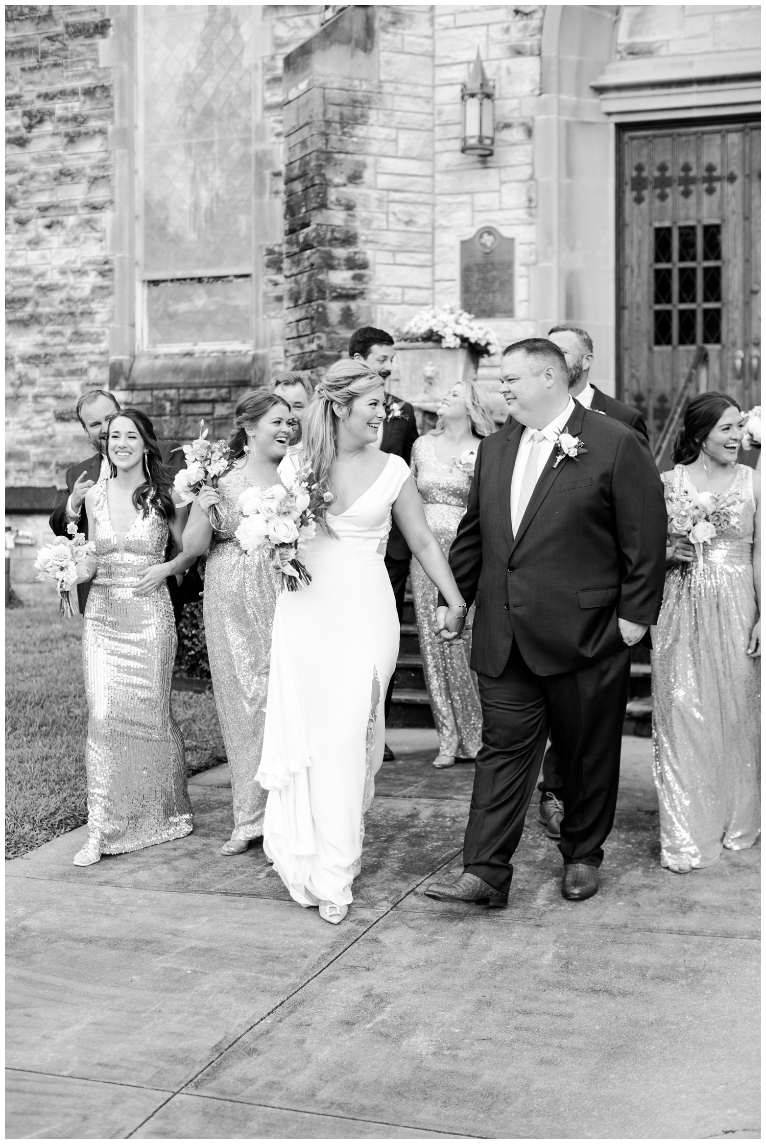 black and white photo bride and groom walking with wedding party in front of St. Marks United Methodist Houston, Texas