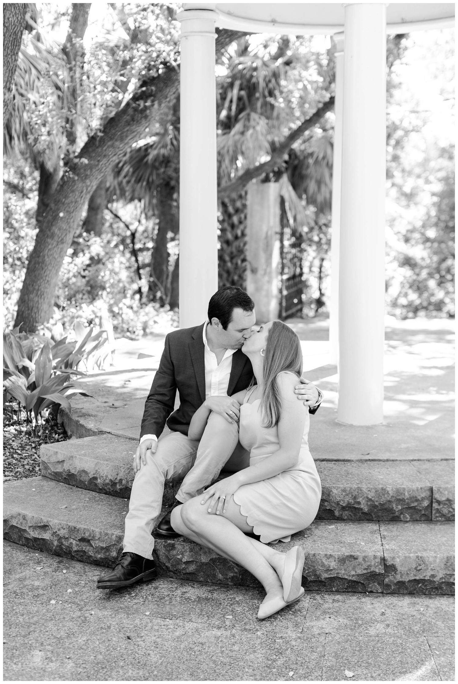 black and white portrait of couple kissing while sitting near columns for Laguna Gloria