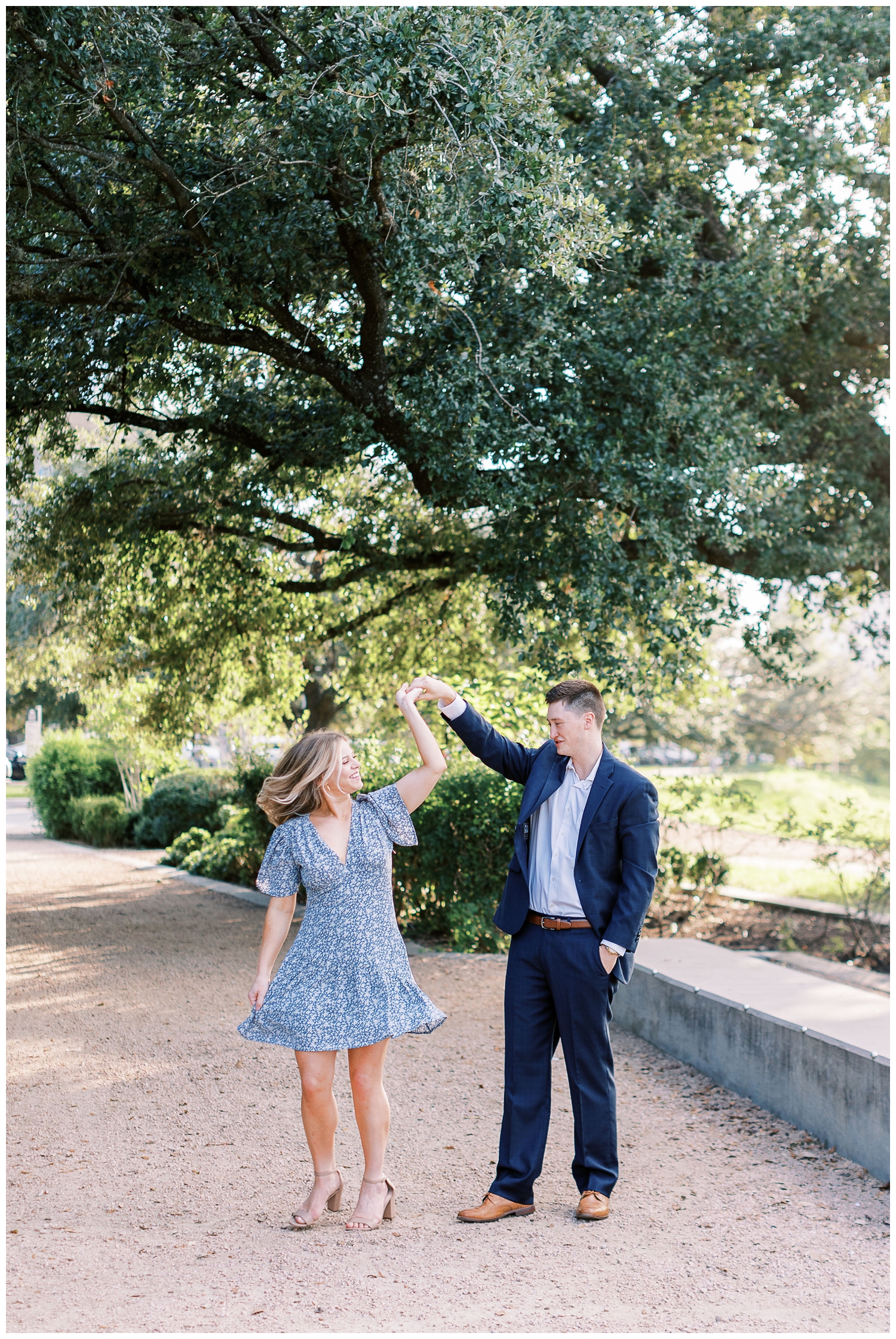 couple in blue dress and blue suit standing under a tree at Eleanor Tinsley engagement session twirling