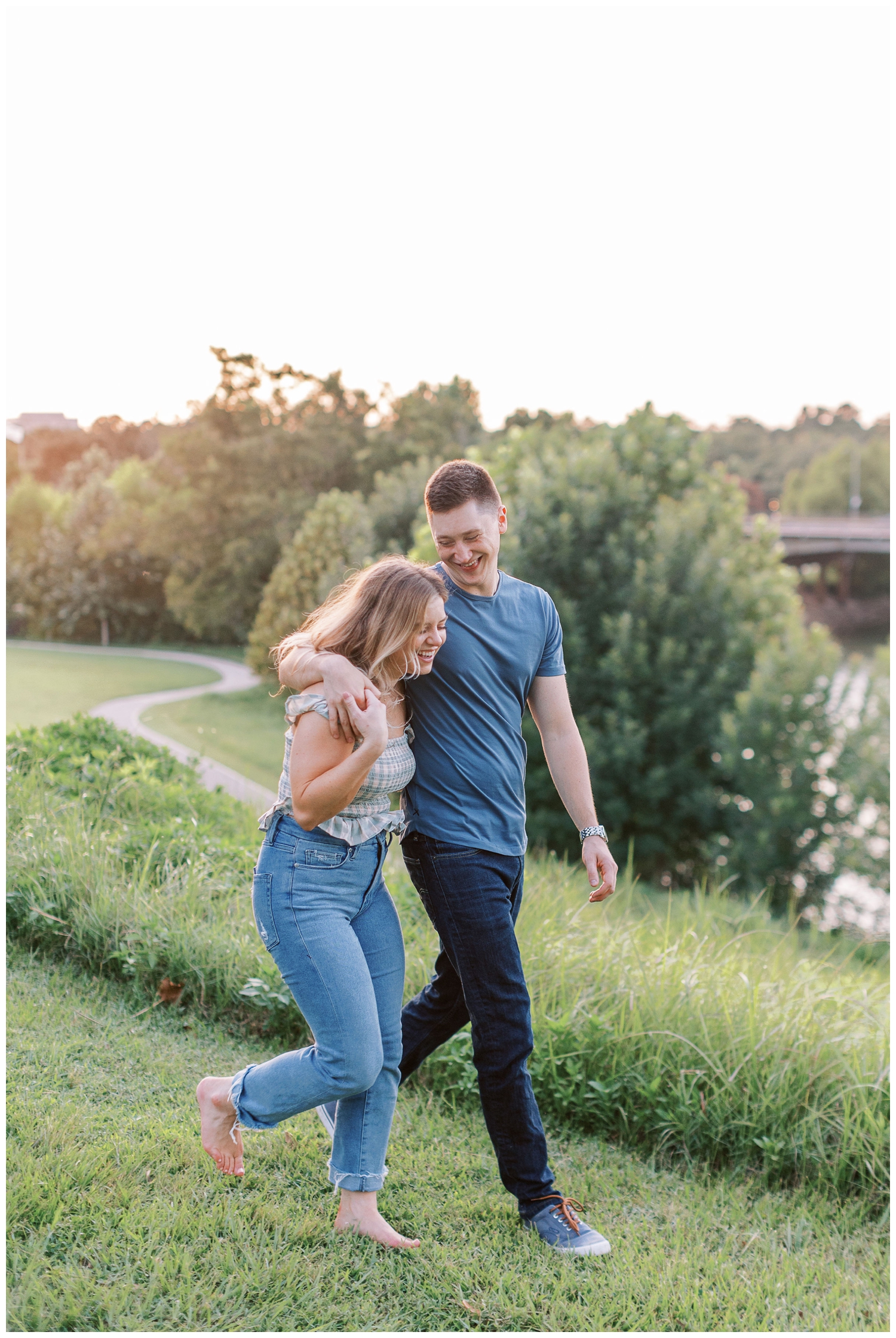 couple laughing and running while hugging on a grassy hill Eleanor Tinsley engagement session