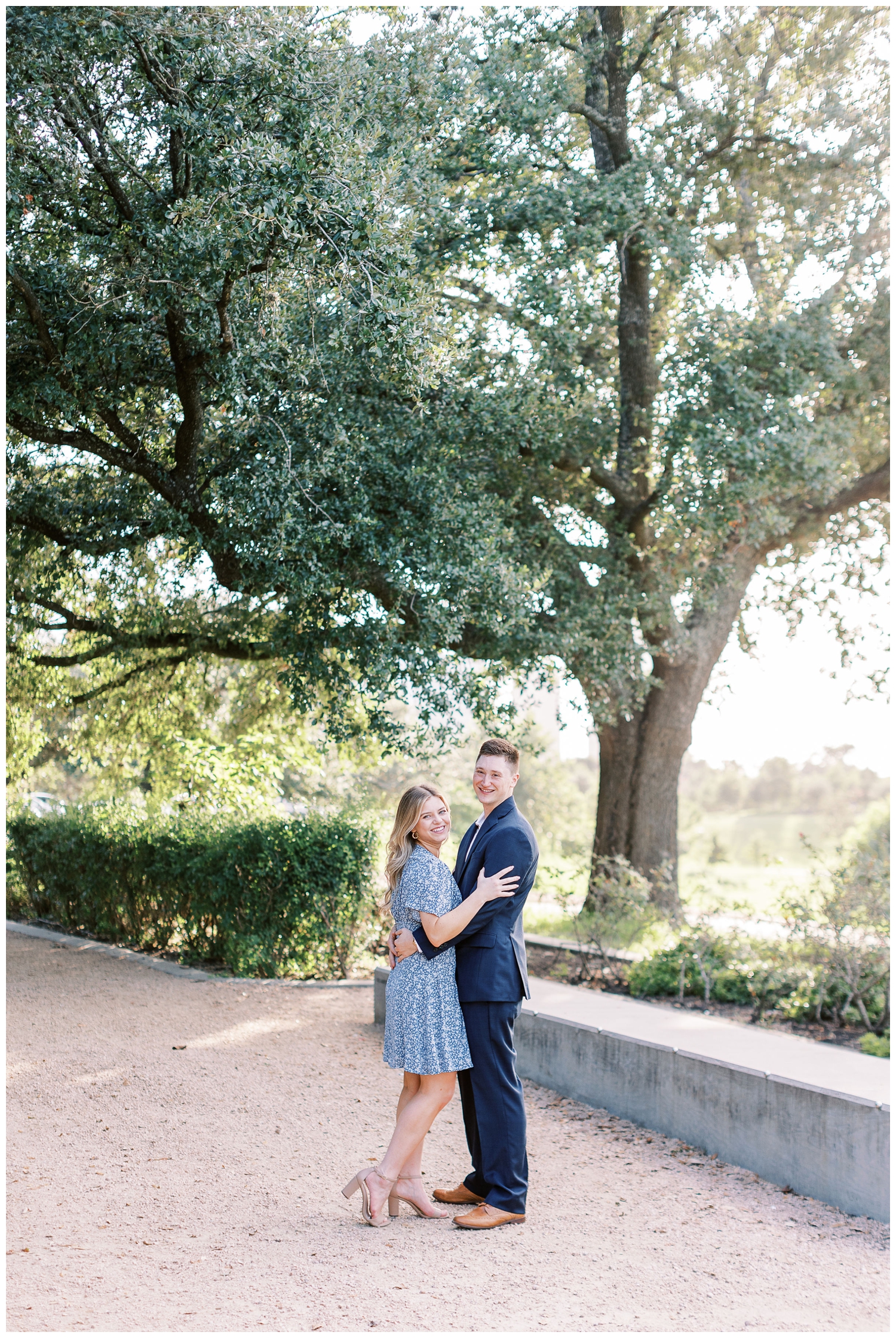 Eleanor Tinsley engagement session with couple in blue suit and dress standing under a tree