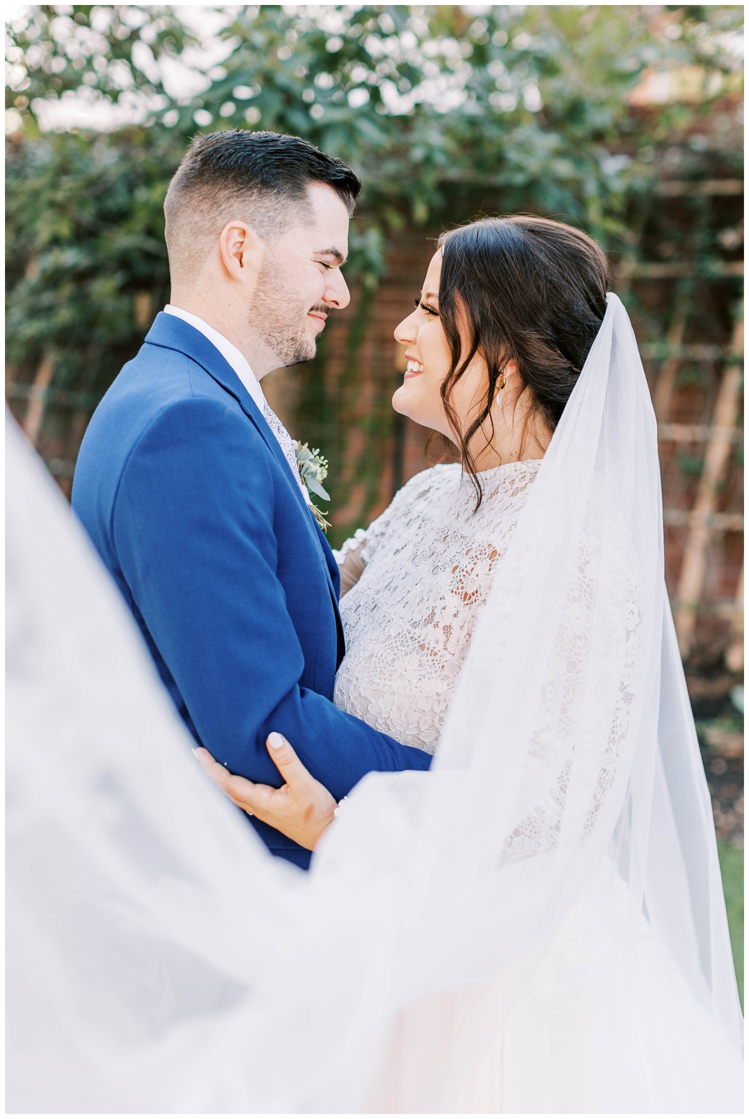 bride and groom portrait with veil swoop groom in blue tux portrait standing under tree for Austin outdoor wedding