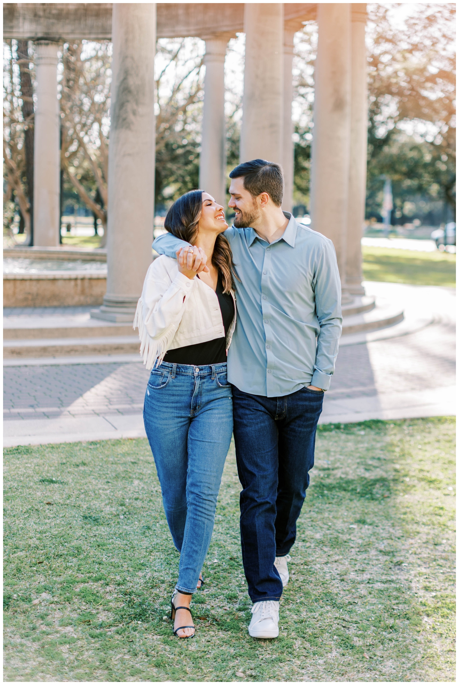 engaged couple walking and looking at each other wearing blue jeans
