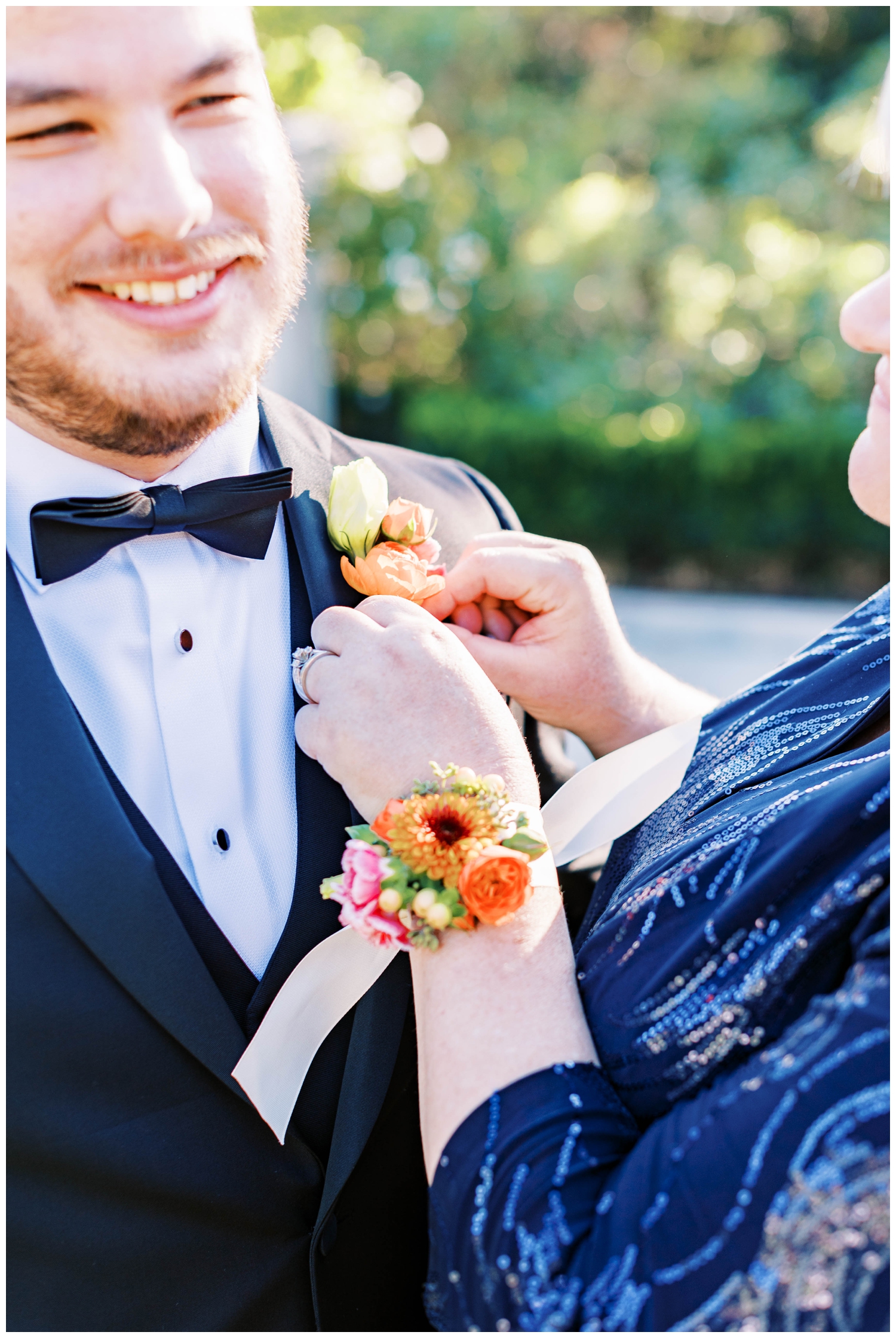 mother of groom pinning pink orange boutonniere on groom at McGovern Centennial Gardens Wedding