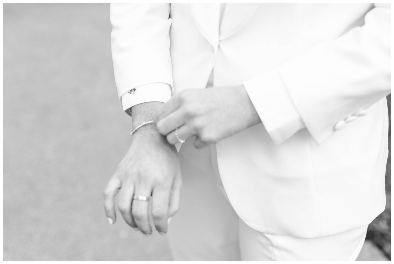 detailed image of bride in white pant suit fastening bracelet