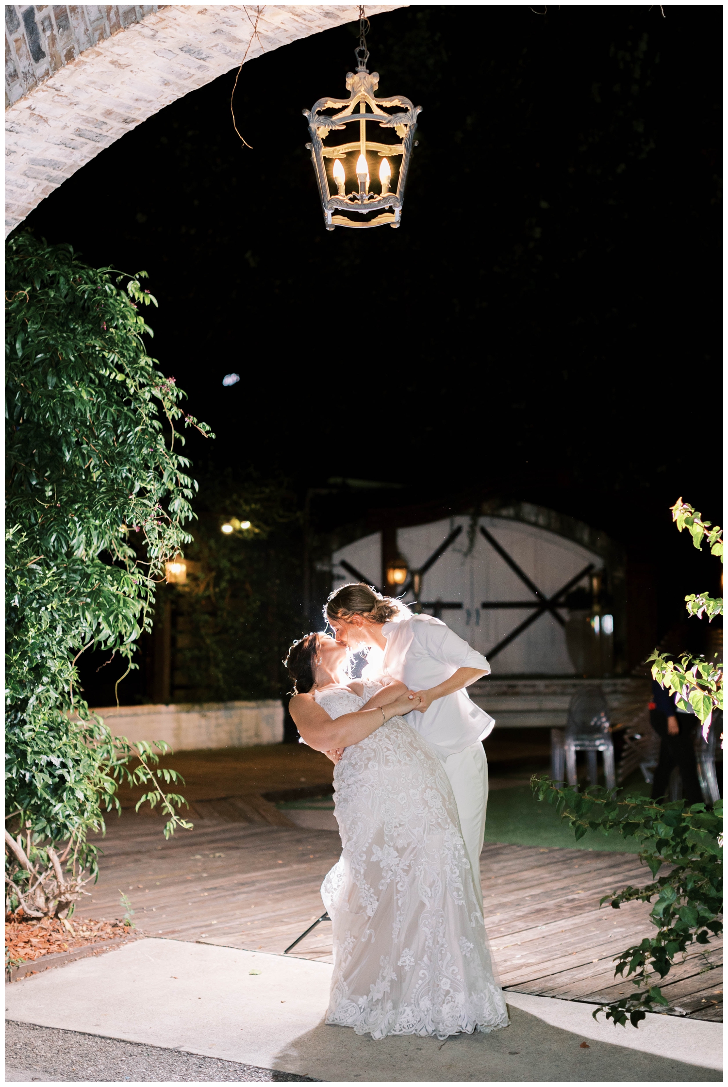 brides kissing during night time portrait at Hughes Manor