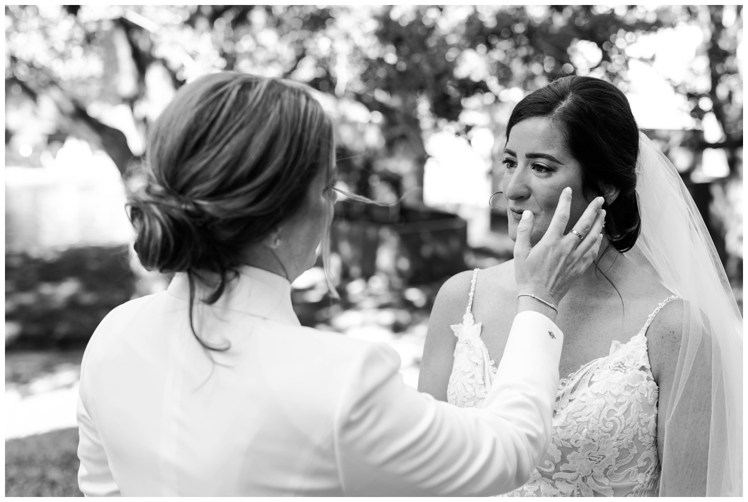 black and white image of bride wiping tear away from bride outdoors Hughes Manor wedding