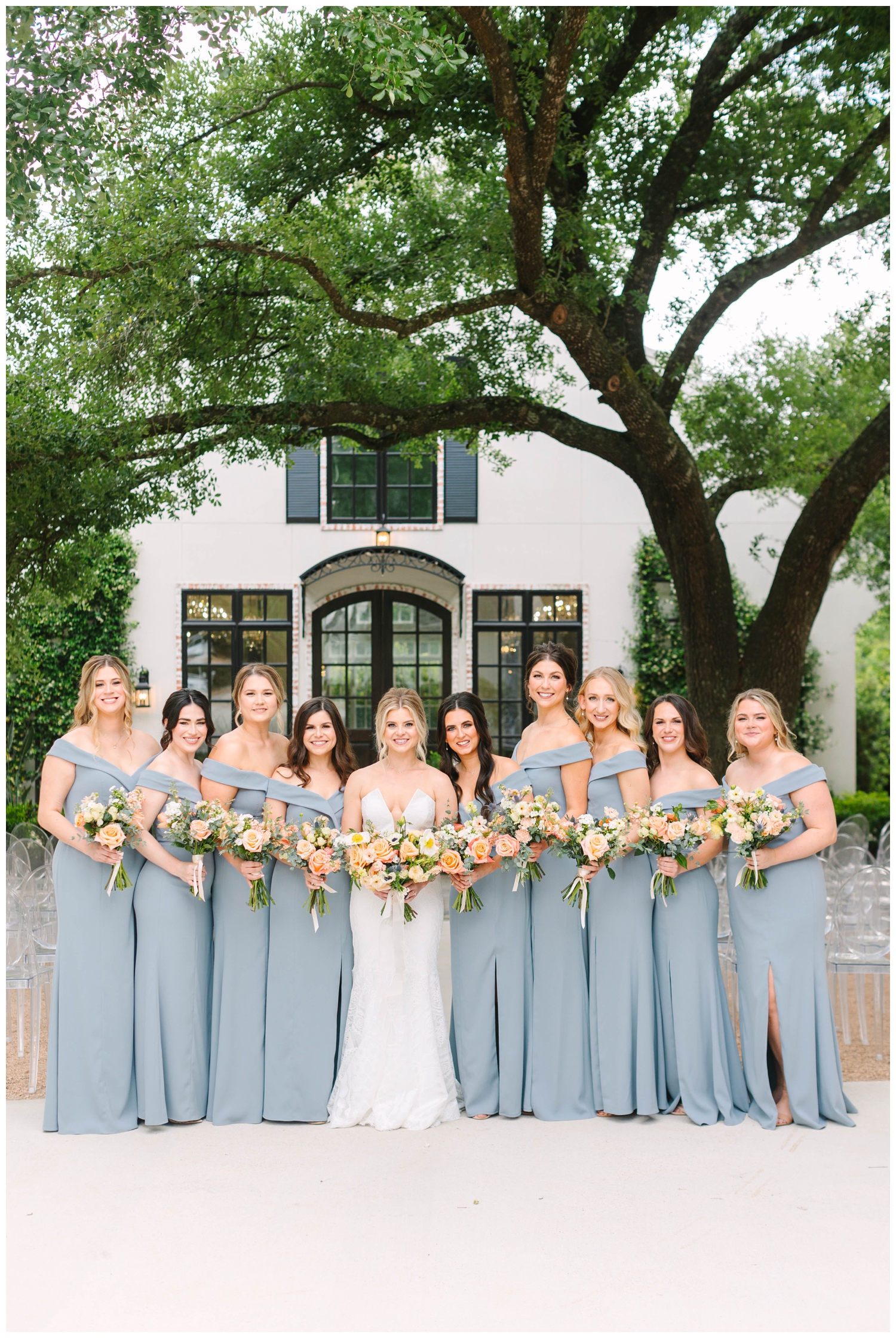 bride and bridesmaids in blue dresses standing under oak tree at The Peach Orchard