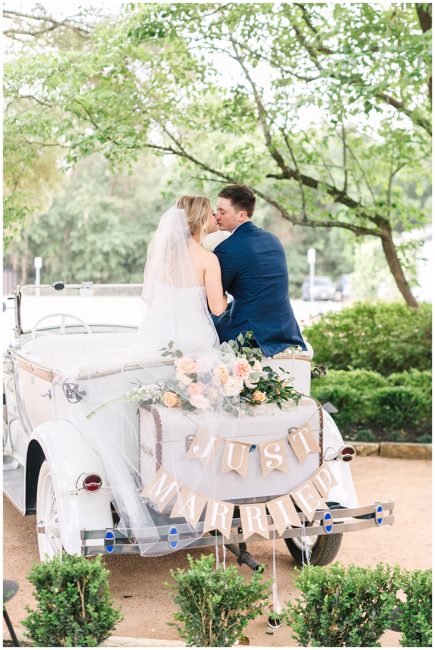 bride and groom kissing in get away vintage car