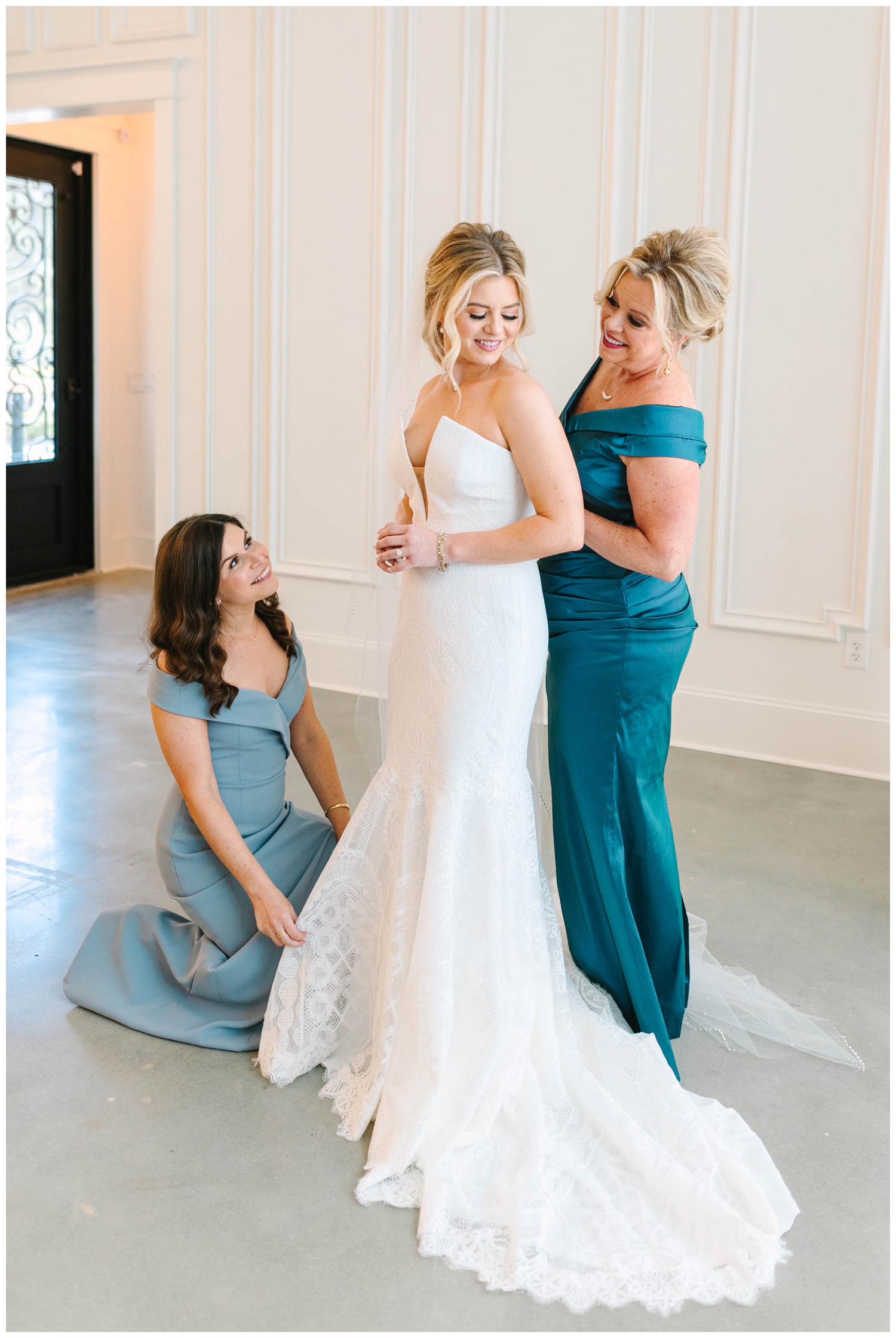 bride getting ready with mom and bridesmaid in a blue dress