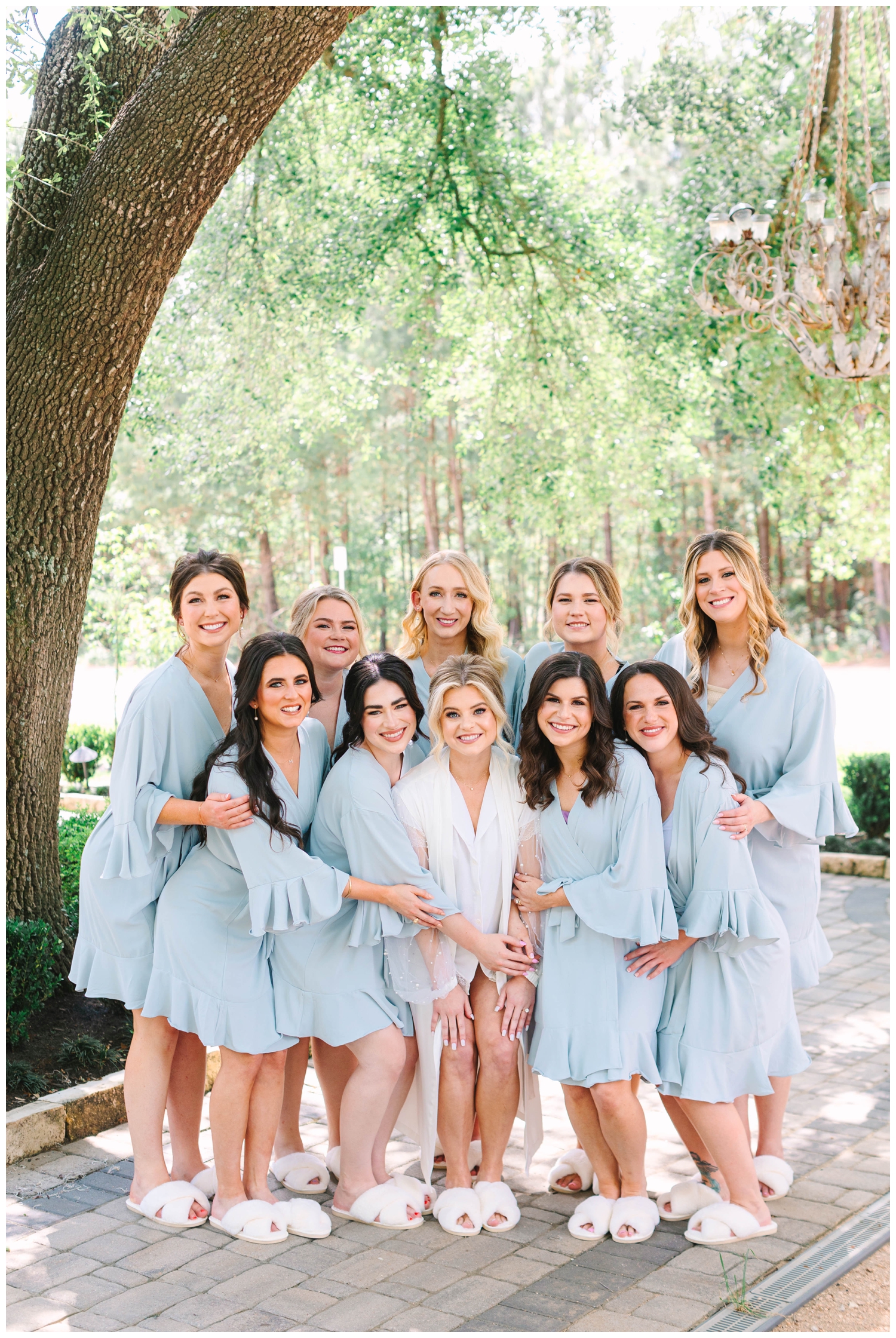 bride in white robe and bridesmaids in blue robe under a tree at The Peach Orchard wedding venue