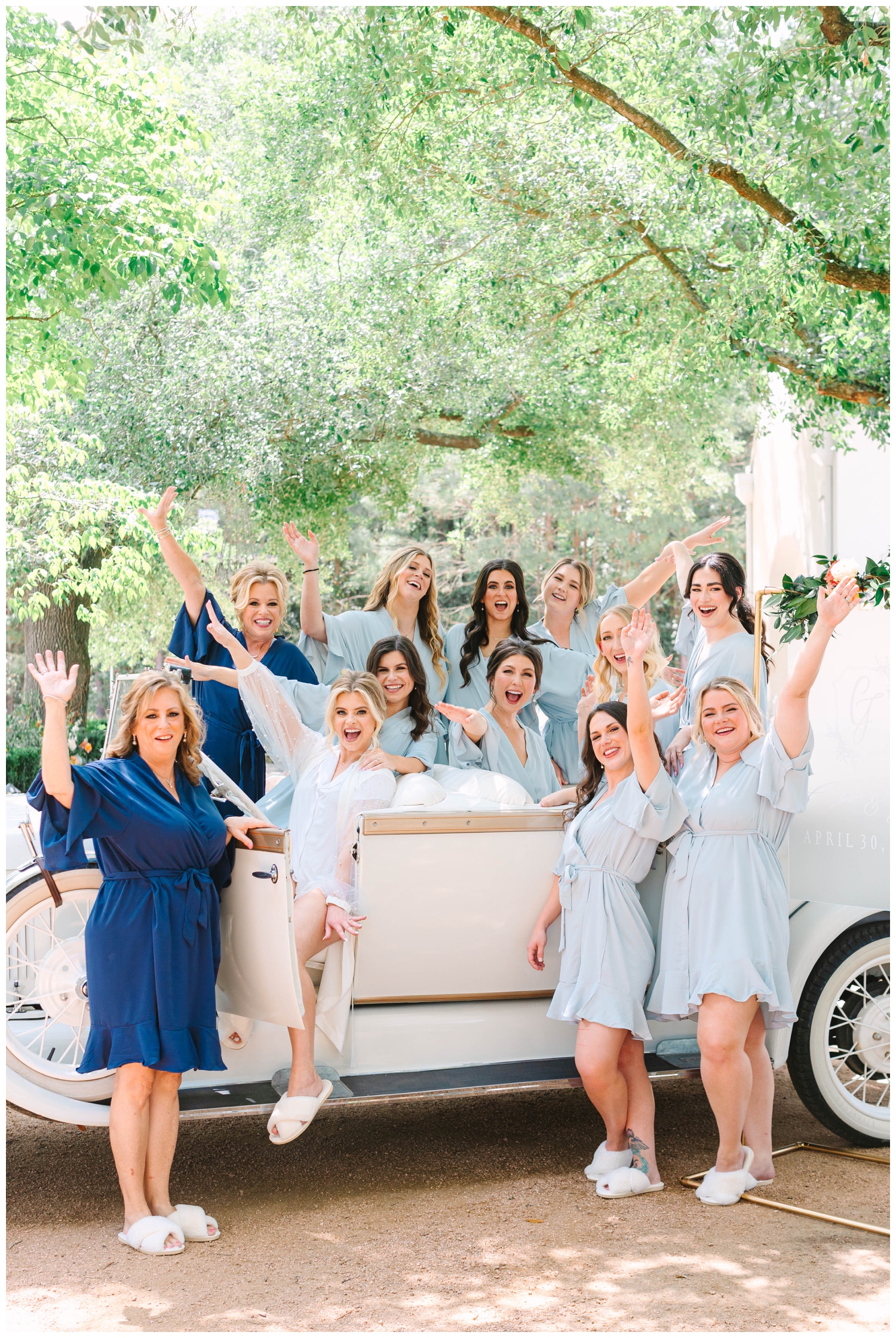 bride and bridesmaids outdoors laughing and sitting inside a classic getaway car