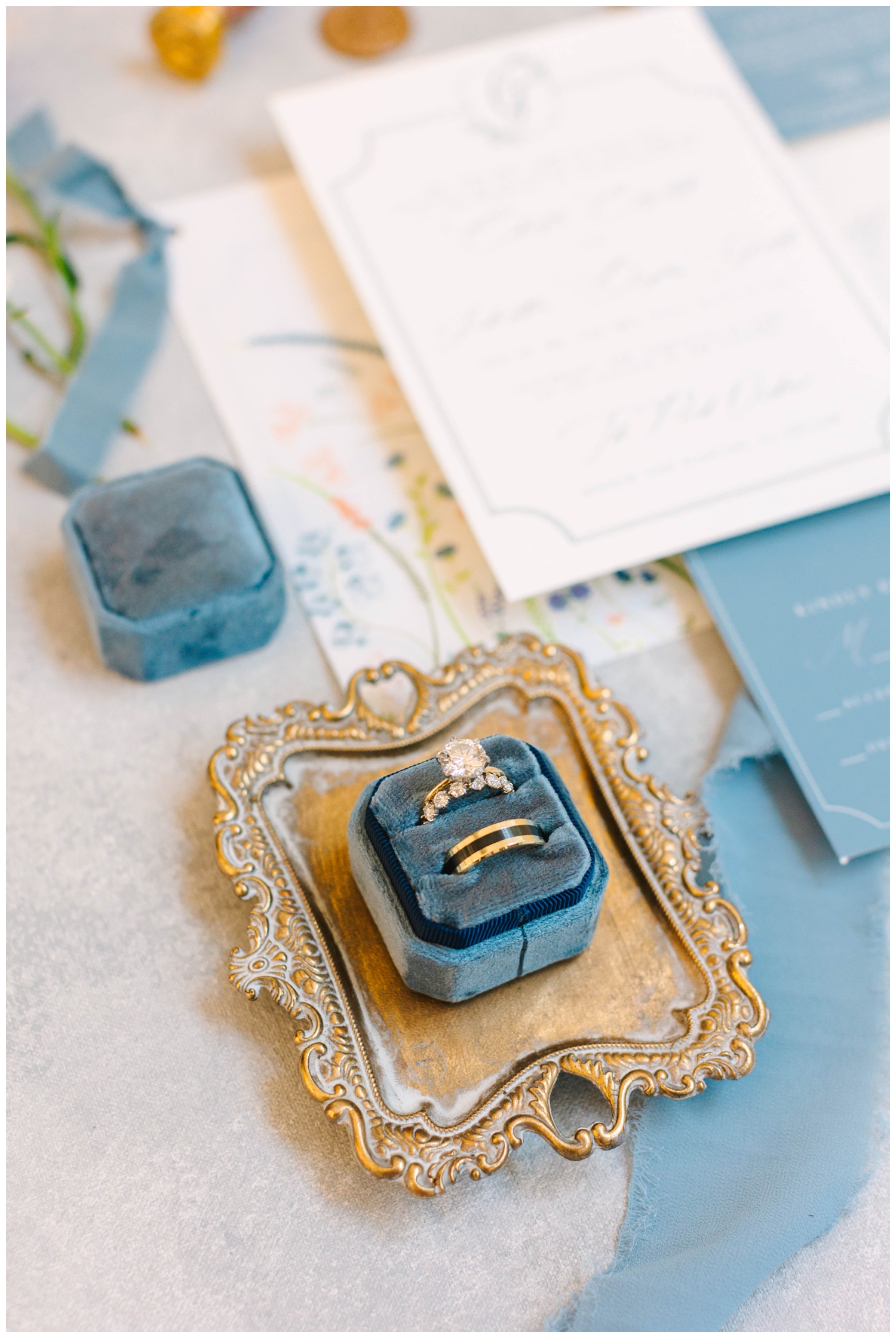 flaylat of wedding ring in blue ring box on gold tray