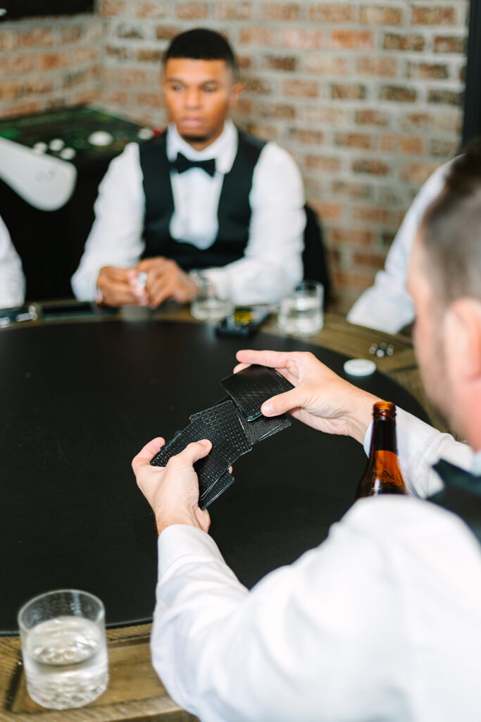 Groom and groomsmen playing cards before wedding ceremony