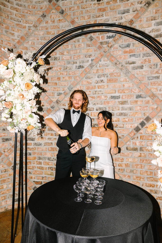 Bride and groom pouring champagne tower during wedding reception