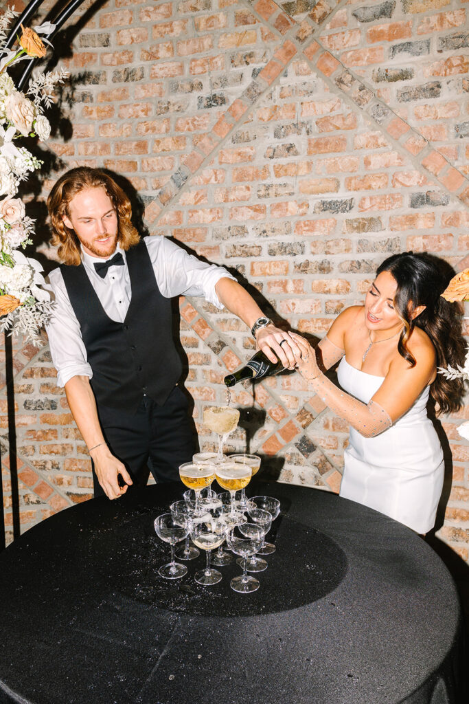 Bride and groom pouring champagne tower during wedding reception