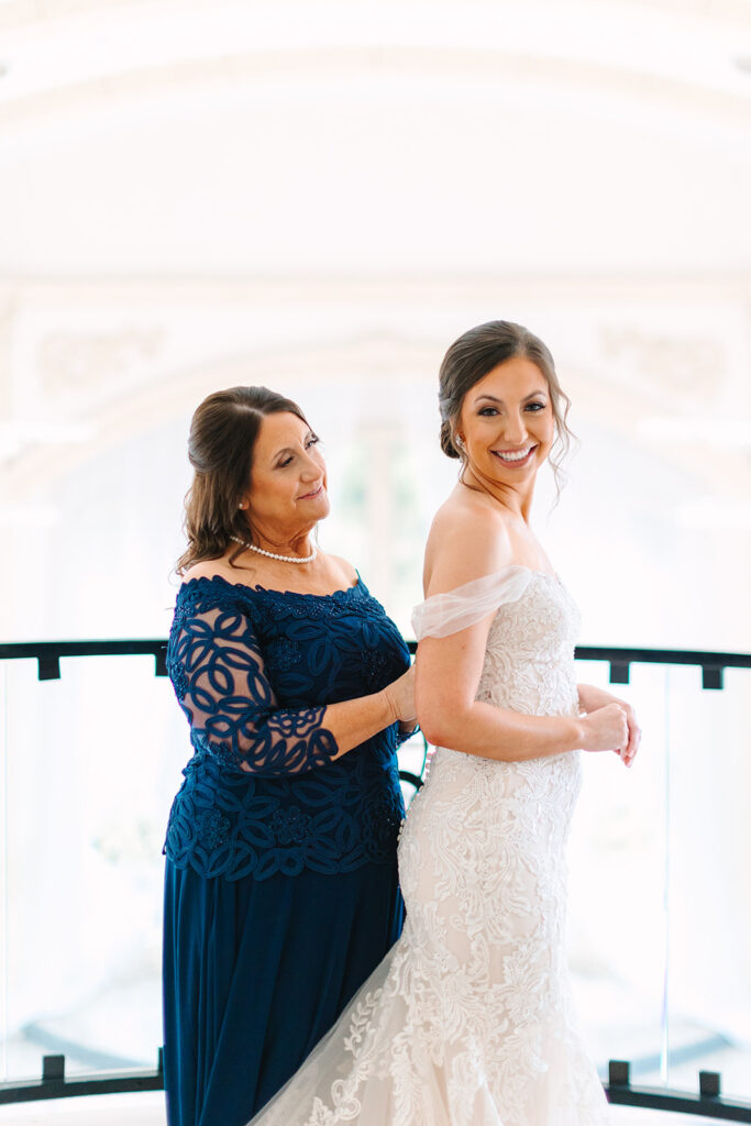 Bride putting wedding dress on with her mother