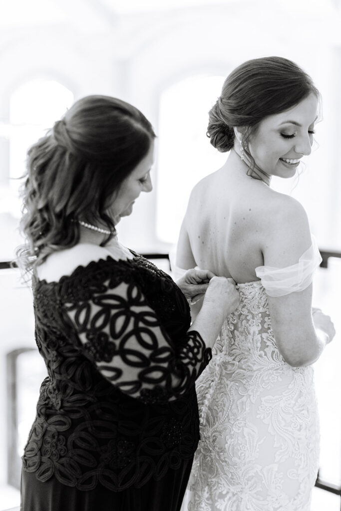 Bride putting wedding dress on with her mother