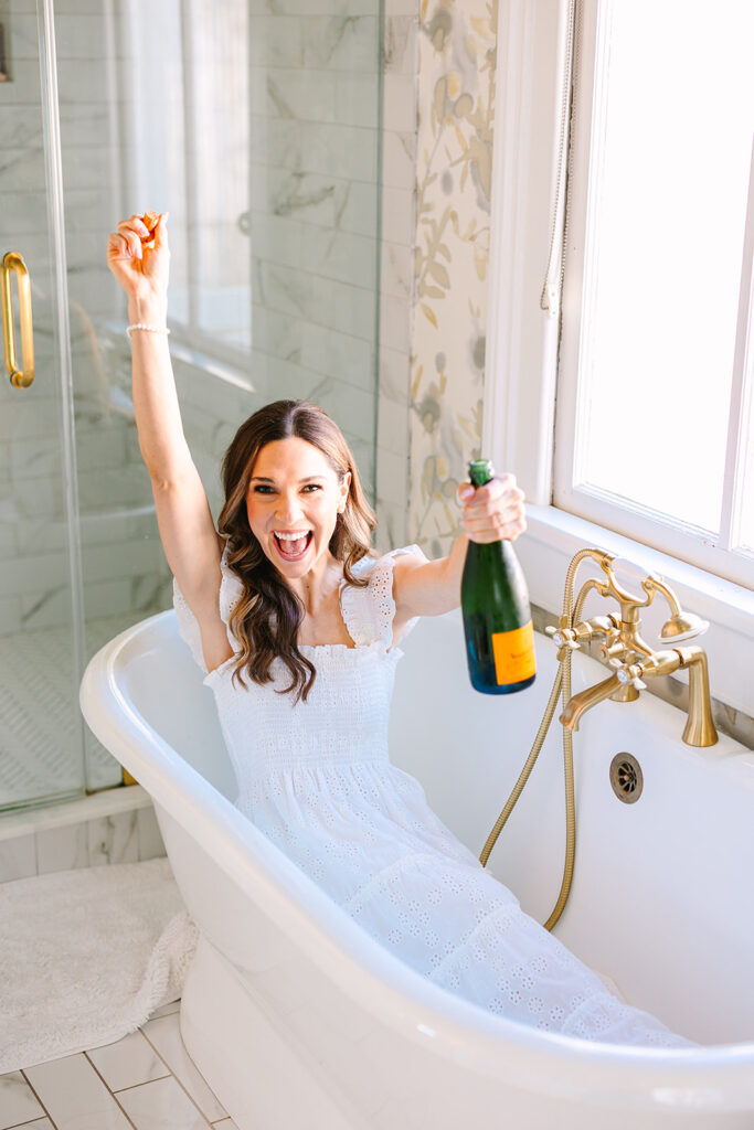 bride popping champagne in bathtub