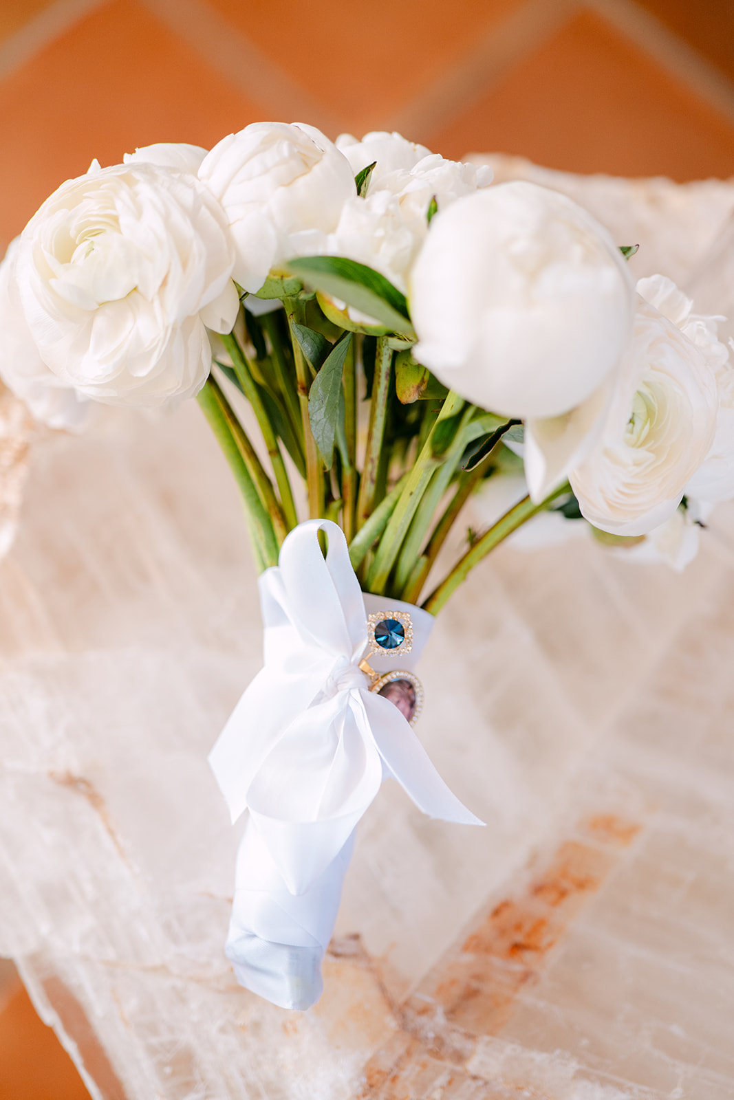 A bouquet of white flowers tied with a white ribbon, resting on a sheer fabric.