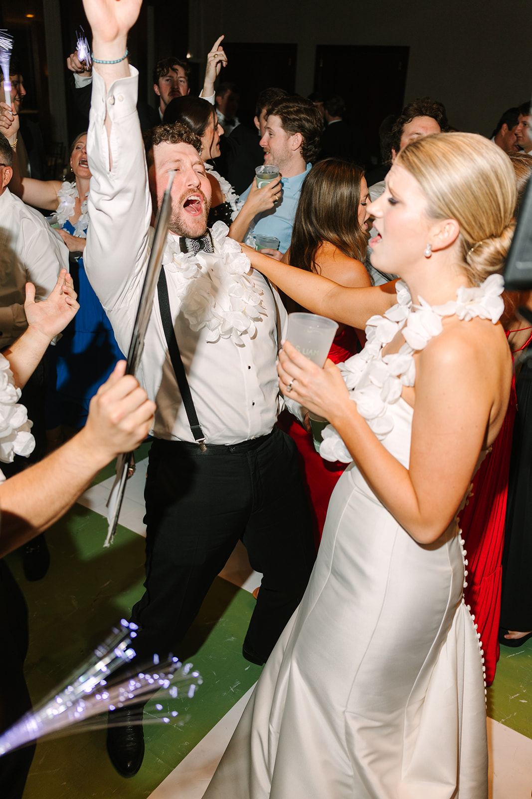 A group of people dressed in formal attire are dancing and socializing at a crowded indoor party.