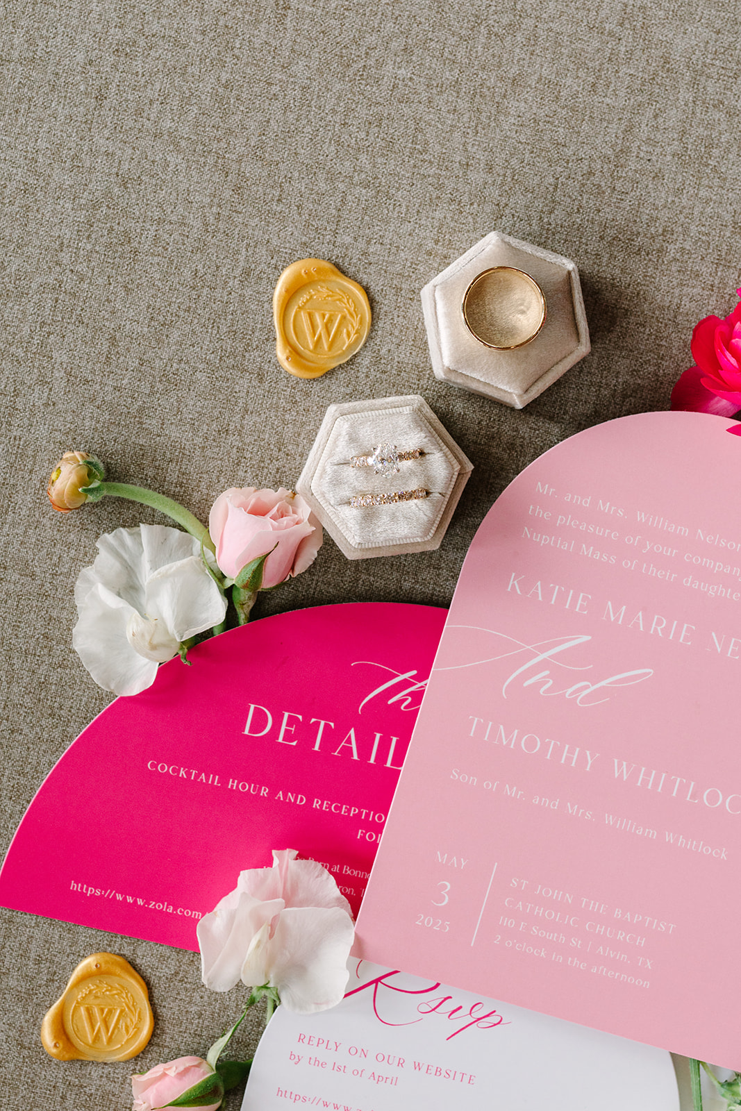 Three pink and white wedding invitations with gold wax seals and assorted flowers arranged around them on a beige surface for a pink summer wedding 