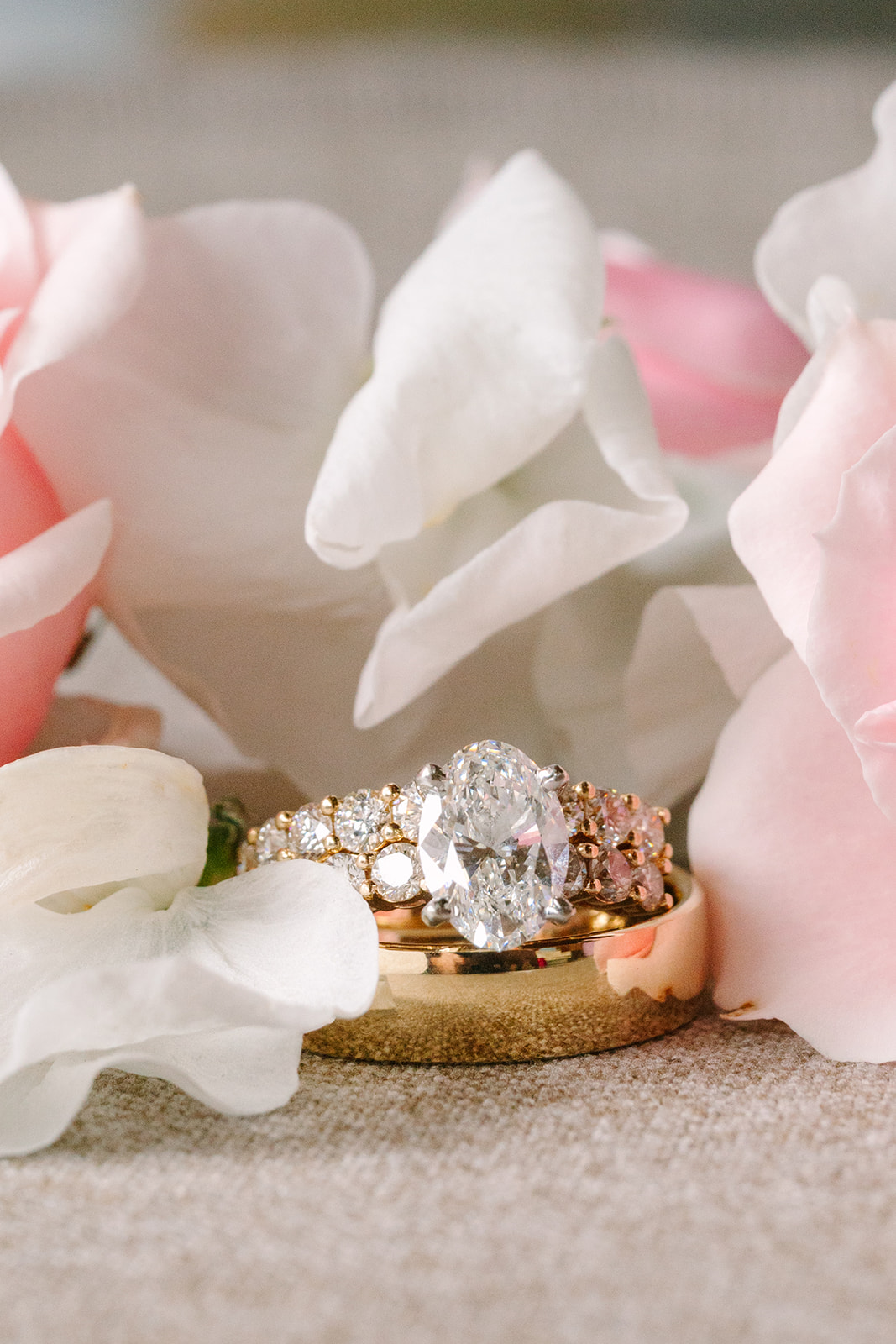 Three pink and white wedding invitations with gold wax seals and assorted flowers arranged around them on a beige surface for a pink summer wedding 