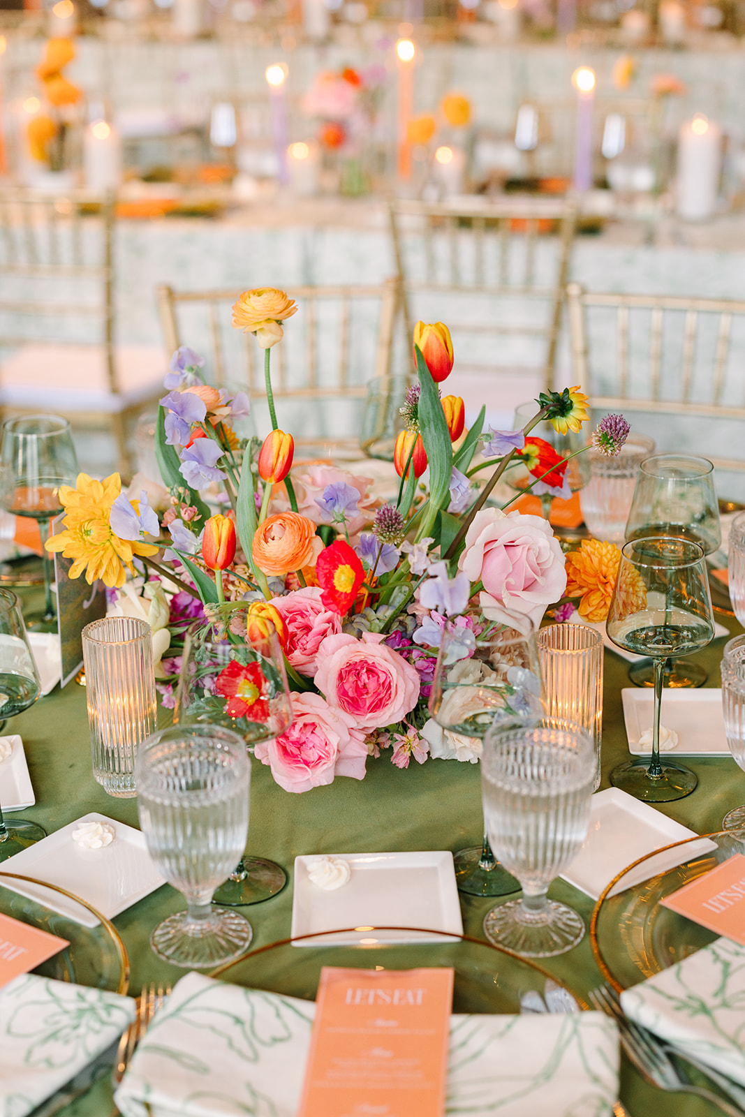 A formal banquet hall with round tables covered in green tablecloths, set for dining, white chairs, a large chandelier, and checkered flooring in the background at the corinthian houston