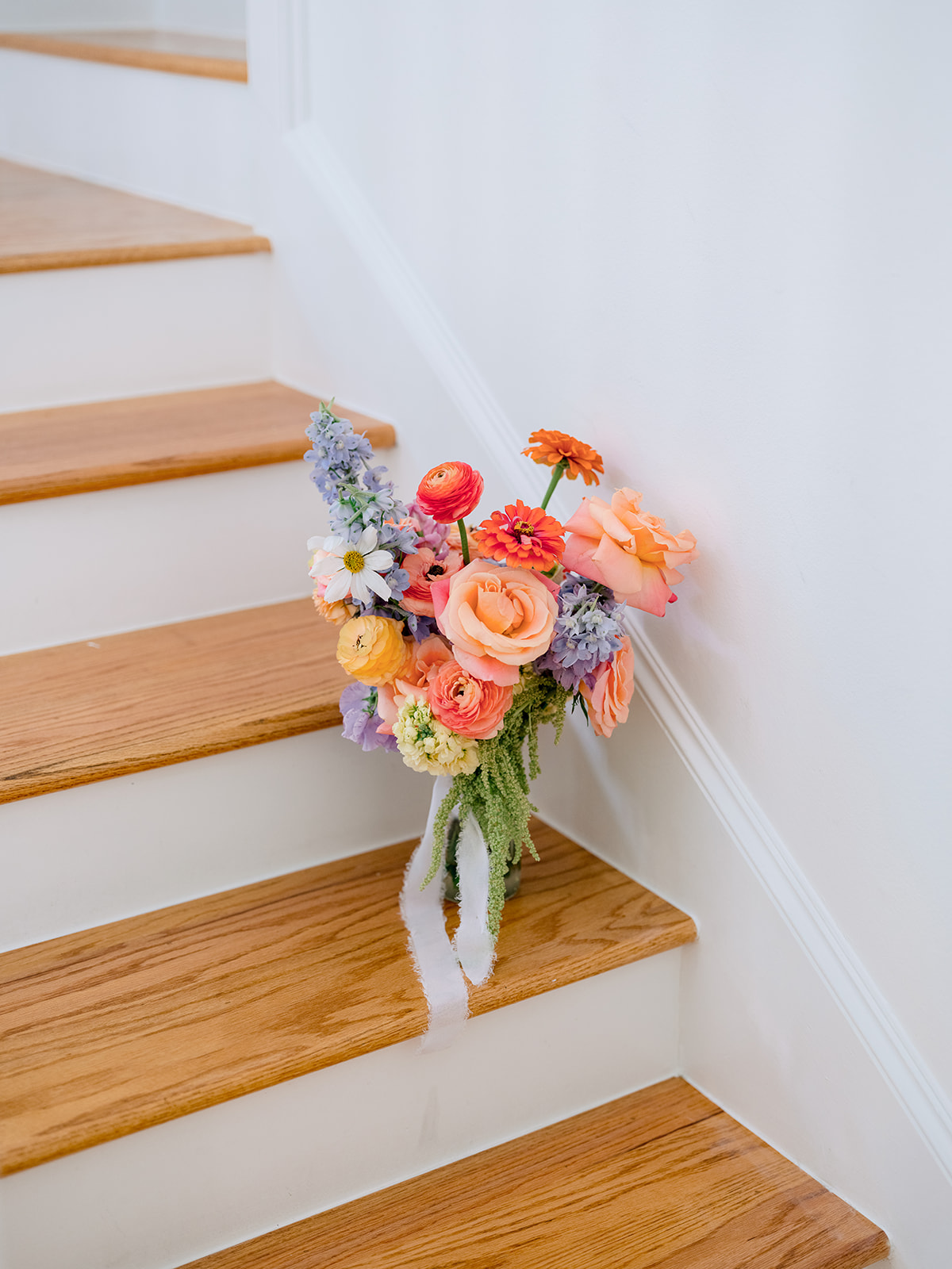 A colorful bouquet of flowers rests against the wall on a wooden staircase.